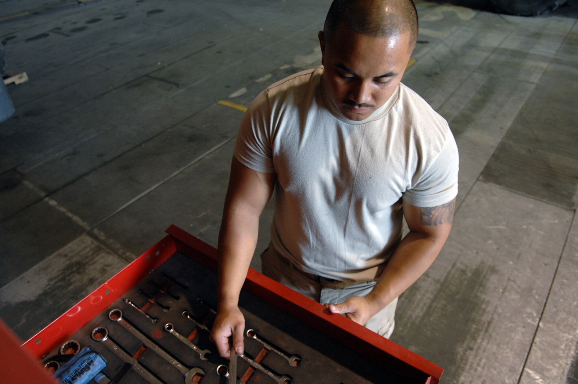 Staff Sgt. Russel Southerland, 376th Air Expeditionary Wing Vehicle Maintenance flight mechanic reaches for a box-end wrench to tighten a clamp on the motor of an R-11 fueler. The special purpose maintainer, deployed from Davis-Monthan Air Force Base, Arizona has worked on the R-11 for nearly a week repairing the transmissions torque converter, returning the vehicle to operational status. (Air Force photo by Tech. Sgt. Michael Voss)
