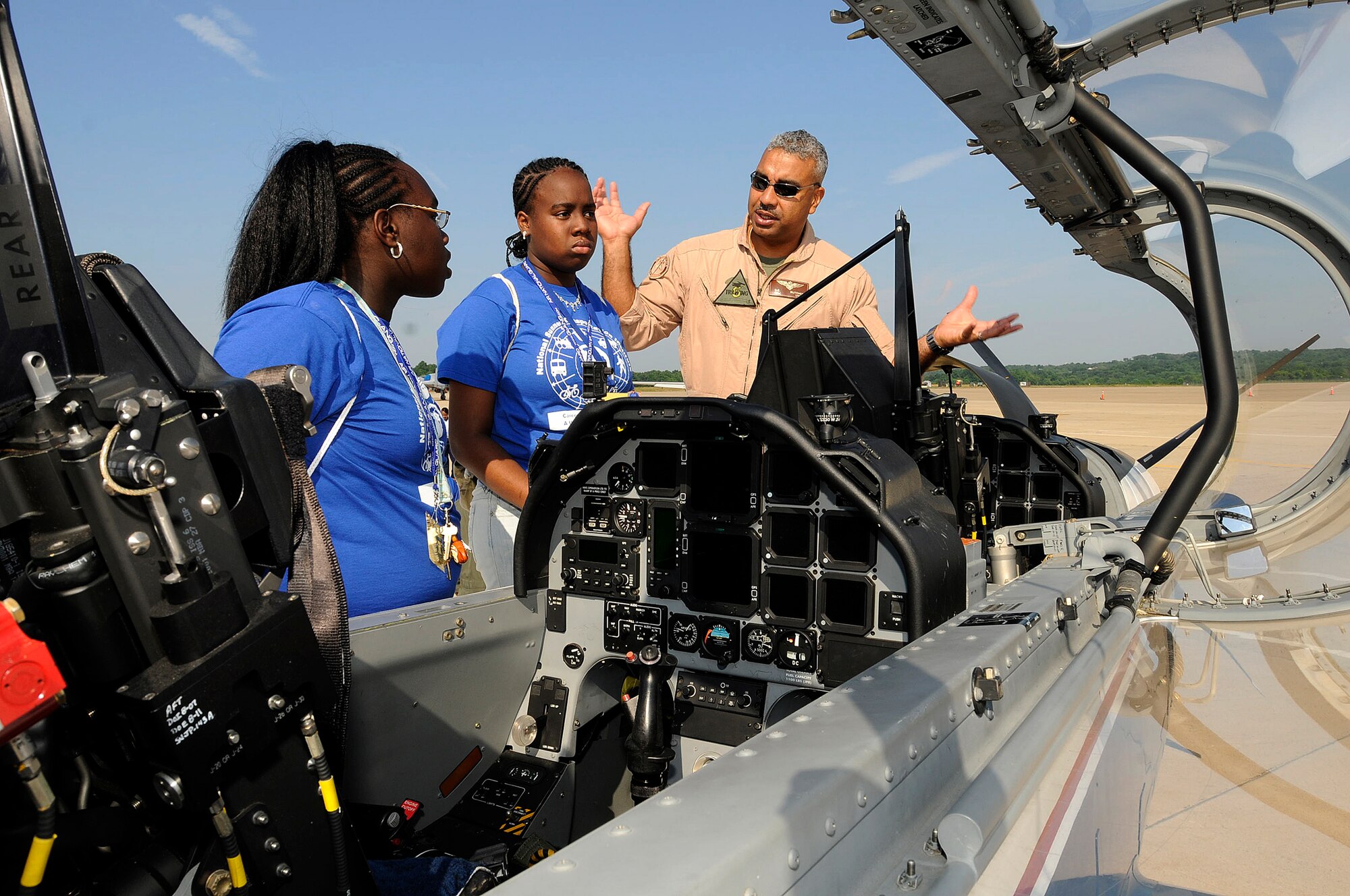 USMC Maj. Gregory Butcher from NAS Pensacola, FL T-6A explains the instruments inside of a T-6A to Regna Felder and her sister Janese Felder from the Summer Transportation Institute, Cheney University, Pa. The 111th Fighter Wing hosted Tuskegee Airman Youth Day on Saturday July 19th.  Young men and women from Greater Philadelphia and Delaware came to ARS Willow Grove to meet Tuskegee Airmen and see up close aircraft such as an A-10, F-16, T-6A and P-3.  