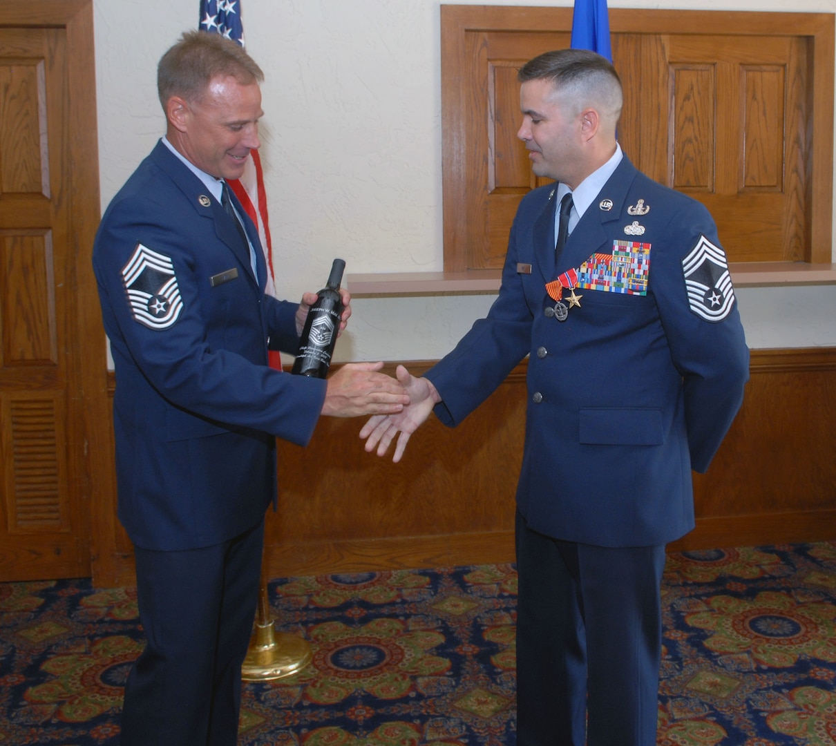 Chief Master Sgt. Joseph May Jr. (right), Air Education and Training Command's explosive ordnance disposal functional manager, accepts a bottle of wine from Chief Master Sgt. David Fain during a ceremony Aug. 1. During the ceremony, Chief May received a triple crown -- he was officially promoted to chief master sergeant and awarded his first Combat Action Medal and second Bronze Star. (U.S. Air Force photo by Rich McFadden)