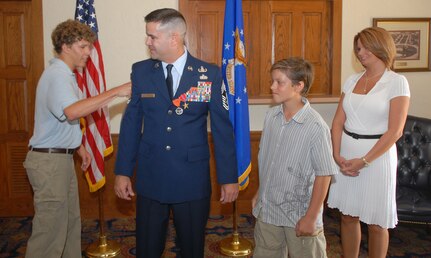 Joseph May punches his dad, Chief Master Sgt. Joseph May, Jr., Air Education and Training Command's explosive ordnance disposal functional manager, in the arm during the promotion portion of his ceremony Aug. 1, as wife, Veronica and son, James, look on. During the ceremony, Chief May received a triple crown -- he was officially promoted to chief master sergeant and awarded his first Combat Action Medal and second Bronze Star. (U.S. Air Force photo by Rich McFadden)