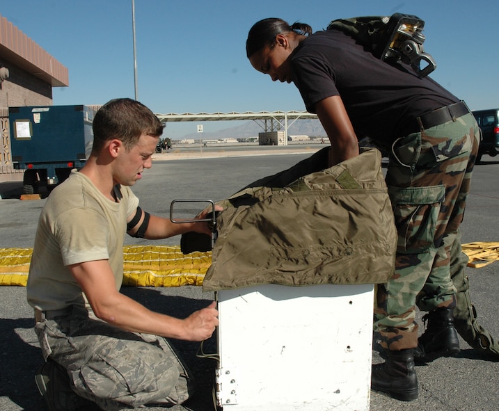 NELLIS AIR FORCE BASE, Nev. --  (from left) Airman 1st Class Tony Iovinelli, 5th Operations Support Squadron aircrew flight equipment journeyman, and Staff Sgt. Christian Lewis, 5th OSS AFE craftsman, field-pack a drag-chute during Red Flag 08-03 July 30. A drag-chute is an extra-large parachute that B-52 pilots deploy during landing to slow the aircraft’s momentum. It is approximately 90 feet long. In all, AFE maintains more than $12 million worth of survival equipment on the 5th Bomb Wing’s B-52s alone. (U.S. Air Force photo by Airman 1st Class Wesley Wright)