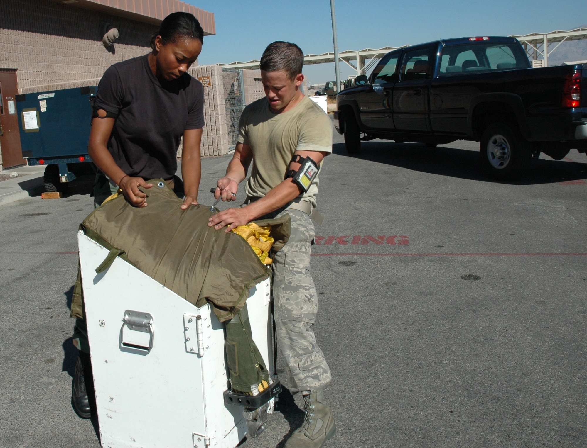 NELLIS AIR FORCE BASE, Nev. -- Staff Sgt. Christian Lewis, 5th Operations Support Squadron aircrew flight equipment craftsman, and Airman 1st Class Tony Iovinelli, 5th OSS AFE journeyman, field-pack a drag-chute during Red Flag 08-03 July 30. A drag-chute is an extra-large parachute that B-52 pilots deploy during landing to slow the aircraft’s momentum. It is approximately 90 feet long. In all, AFE maintains more than $12 million worth of survival equipment on the 5th Bomb Wing’s B-52s alone. (U.S. Air Force photo by Airman 1st Class Wesley Wright)