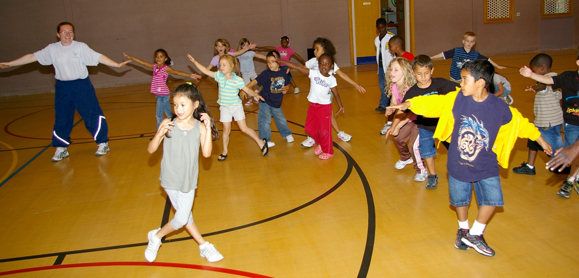 Tech. Sgt. Angel Rios, 100th Force Support Squadron Fitness Center fitness program director, shows children at the RAF Mildenhall Youth Center some warm-up exercises before starting the mini circuit class Aug. 1. The 100th FSS put together the class for children at the youth center during the summer holidays to provide extra ways to keep children entertained. (U.S. Air Force photo by Karen Abeyasekere) 