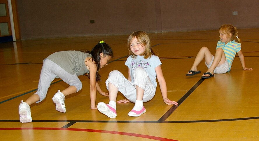 Angelina Felan, left, 6, 48th Equipment Maintenance Squadron family member, Jade Rose, 6, 100th Maintenance Operations Squadron family member, and Raya Hurst, 5, 95th Reconnaissance Squadron family member, do some crab crawls during a specially-devised circuit class at the youth center Aug. 1. (U.S. Air Force photo by Karen Abeyasekere) 