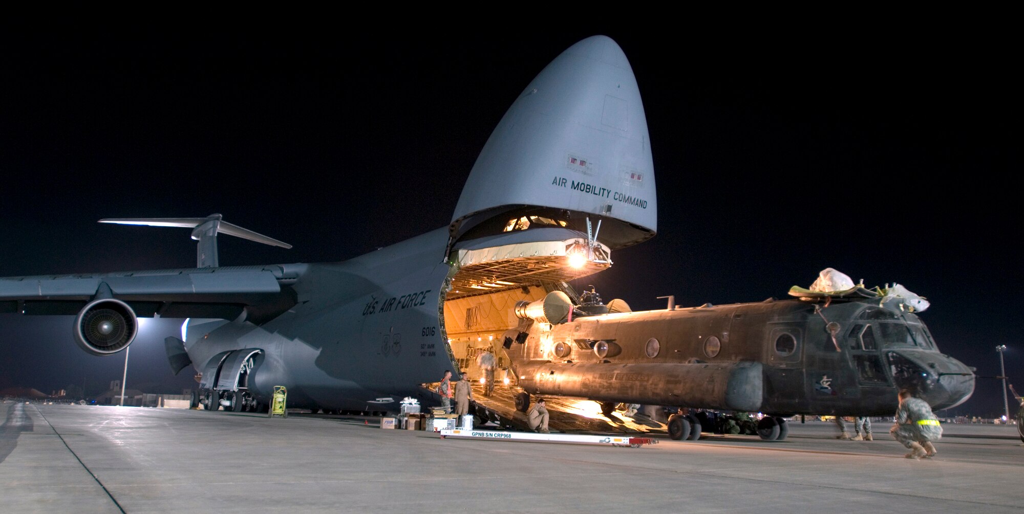 JOINT BASE BALAD, Iraq -- A C-5 Galaxy crew loads a CH-47D Chinook heavy lift helicopter into its cargo bay here Aug. 3. Joint Base Balad processes more than 950 cargo aircraft, 12,000 tons of cargo and 19,000 passengers per month, making it the busiest aerial port operation in the Department of Defense. The C-5 is deployed from the 22nd Airlift Squadron at Travis Air Force Base, Calif. The Chinook belongs to the Army's Bravo Company, 1st Battalion, 52nd Aviation Regiment, which is deployed to Al Toqaddum, Iraq. (U.S. Air Force photo/Airman 1st Class Jason Epley)