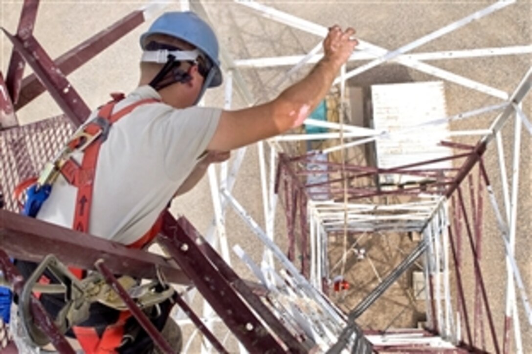 U.S. Air Force Senior Airman George Carameta, lowers an aircraft obstruction light down to Staff Sgt. Ray Stetler. Carameta and Stetler are assigned to the 407th Expeditionary Communications Squadron, Ali Air Base, Iraq, Aug. 2, 2008. The lighting keeps aircraft from colliding into towers when visibility is low. 