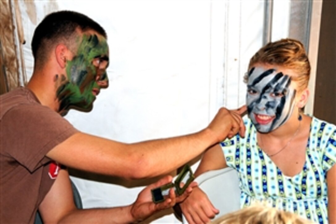U.S. Navy Seaman Steven Day, assigned to Amphibious Construction Battalion 1, paints camouflage face paint on a visitor on family day during Exercise Pacific Strike 2008 on Red Beach in Camp Pendleton, Calif., Aug 2, 2008. 
