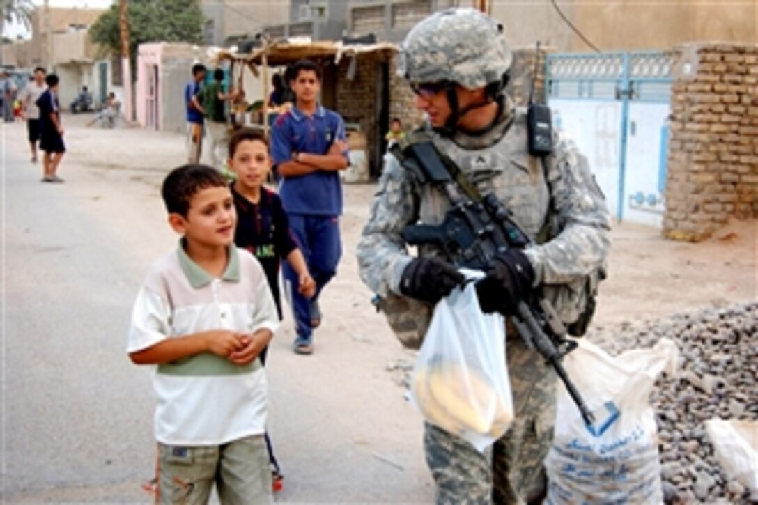 U.S. Army Cpl. Michael Tejada patrols down a street while talking with a boy in Istaqlal Qada, northeast of Baghdad, July 27, 2008, after purchasing bananas from a market. Tejada is a mortar section leader assigned to 25th Infantry Division's Company B, 1st Battalion, 27th Infantry Regiment, 2nd Stryker Brigade Combat Team.

