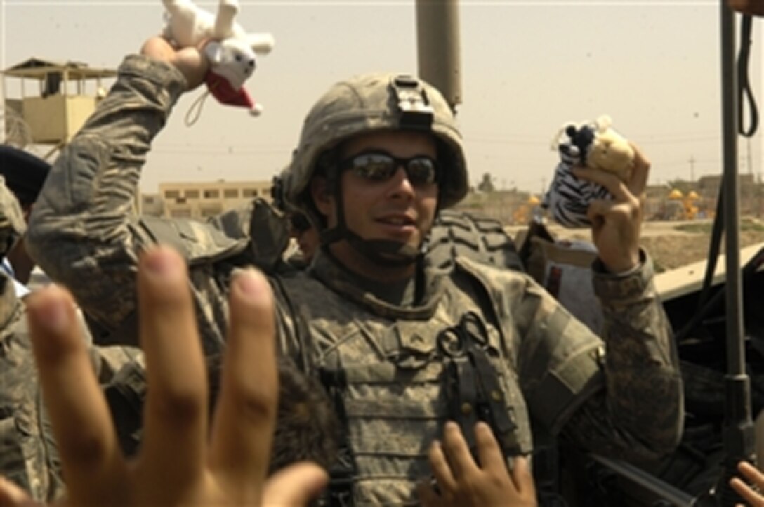 U.S. Army Cpl. Michael McNally hands out stuffed animals to Iraqi children during a routine visit to the Hussein Iraqi Police Station in Diwaniyah, Iraq, on July 30, 2008.  McNally is assigned to the 16th Military Police Brigade, 511th Military Police Company, 1st Platoon, 2nd Squad.  