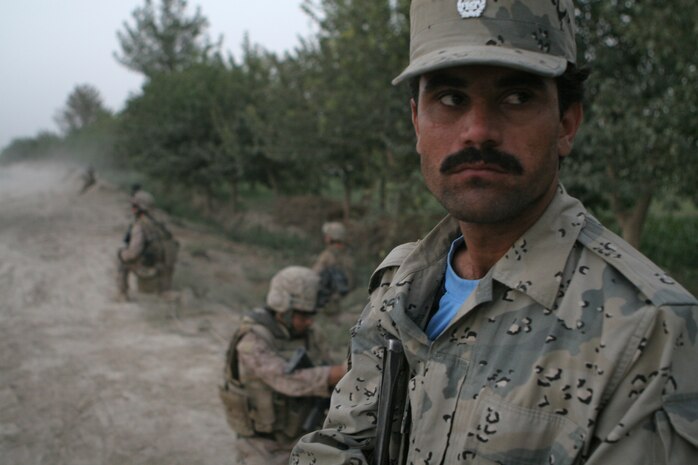 An Afghanistan National Border Patrolmen watches as Marines perform a security patrol in Garmsir.