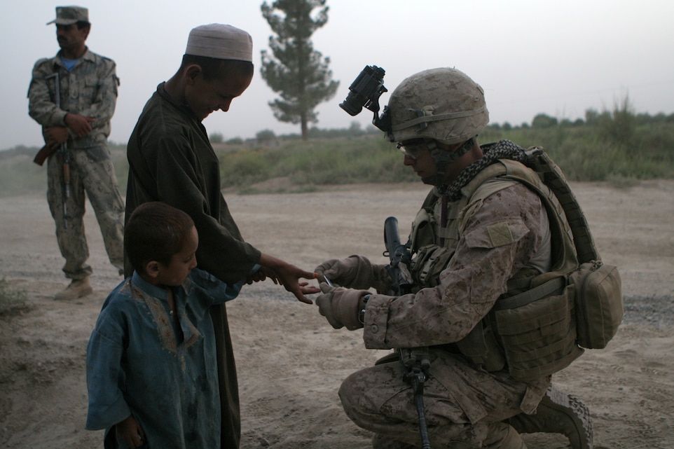 A Marine with A Comapny, Battalion Landing Team 1st Battalion, 6th Marine Regiment, 24th Marine Expeditionary Unit, shares some gum with kids his patrol encountered in the Garmsir city district of Helmand Province.  Marines have been training and conducting joint patrols with Afghanistan National Border Patrolmen to help prepare them to take over security operations once the Marines redeploy.