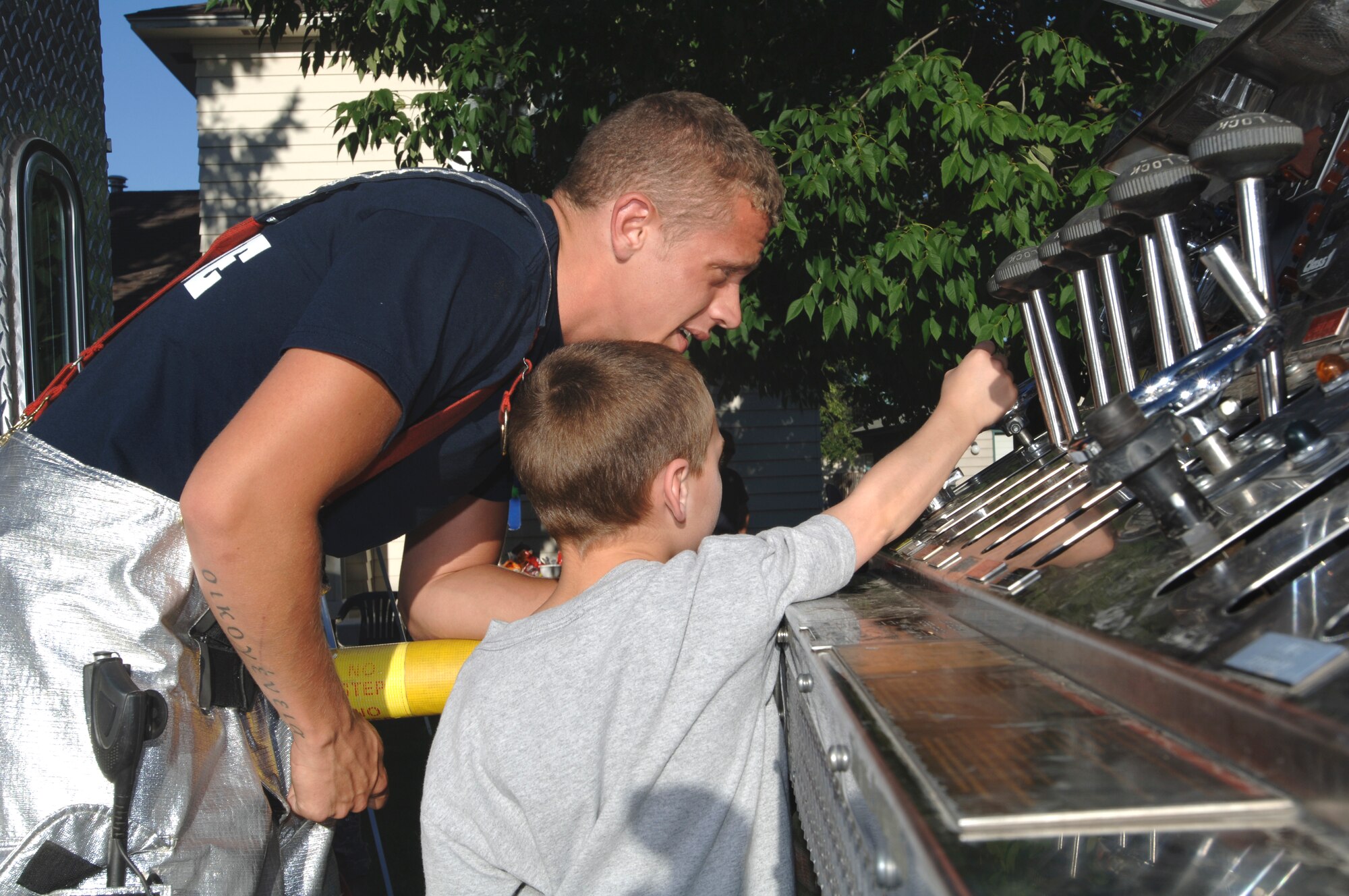 FAIRCHILD AIR FORCE BASE, Wash. – Airman 1st Class Trevor Krause, 92nd Civil Engineer Squadron firefighter, shows Jacob Frisk, 6, how to operate a fire truck at National Night Out Aug. 5. A fire truck and ambulance were on display for neighboring children to explore. (U.S. Air Force photo / Airman 1st Class Melissa Barnett)