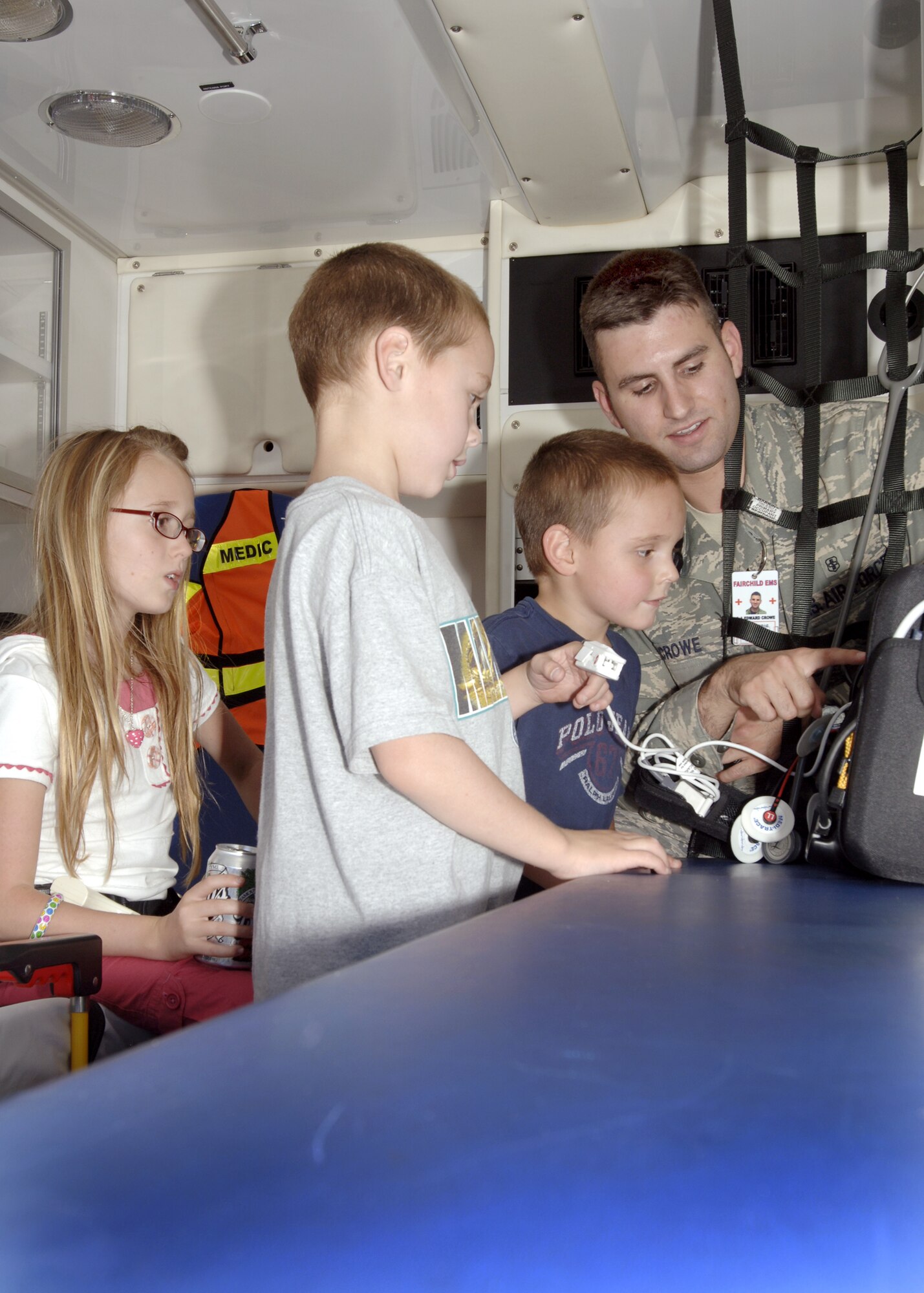 FAIRCHILD AIR FORCE BASE, Wash. –  Senior Airman Edward Crowe, 92nd Medical Operations Squadron, aerospace medicine services technician, measures 6-year-old Jacob Frisk’s heart rate while Logan Frisk, 5, and Destiny Stoner, 10, patiently wait their turn in an ambulance, which was on display for National Night Out Aug. 5. Three houses on base hosted National Night Out parties to combat drug and crime prevention in their communities and provide home safety education. (U.S. Air Force photo / Airman 1st Class Melissa Barnett)