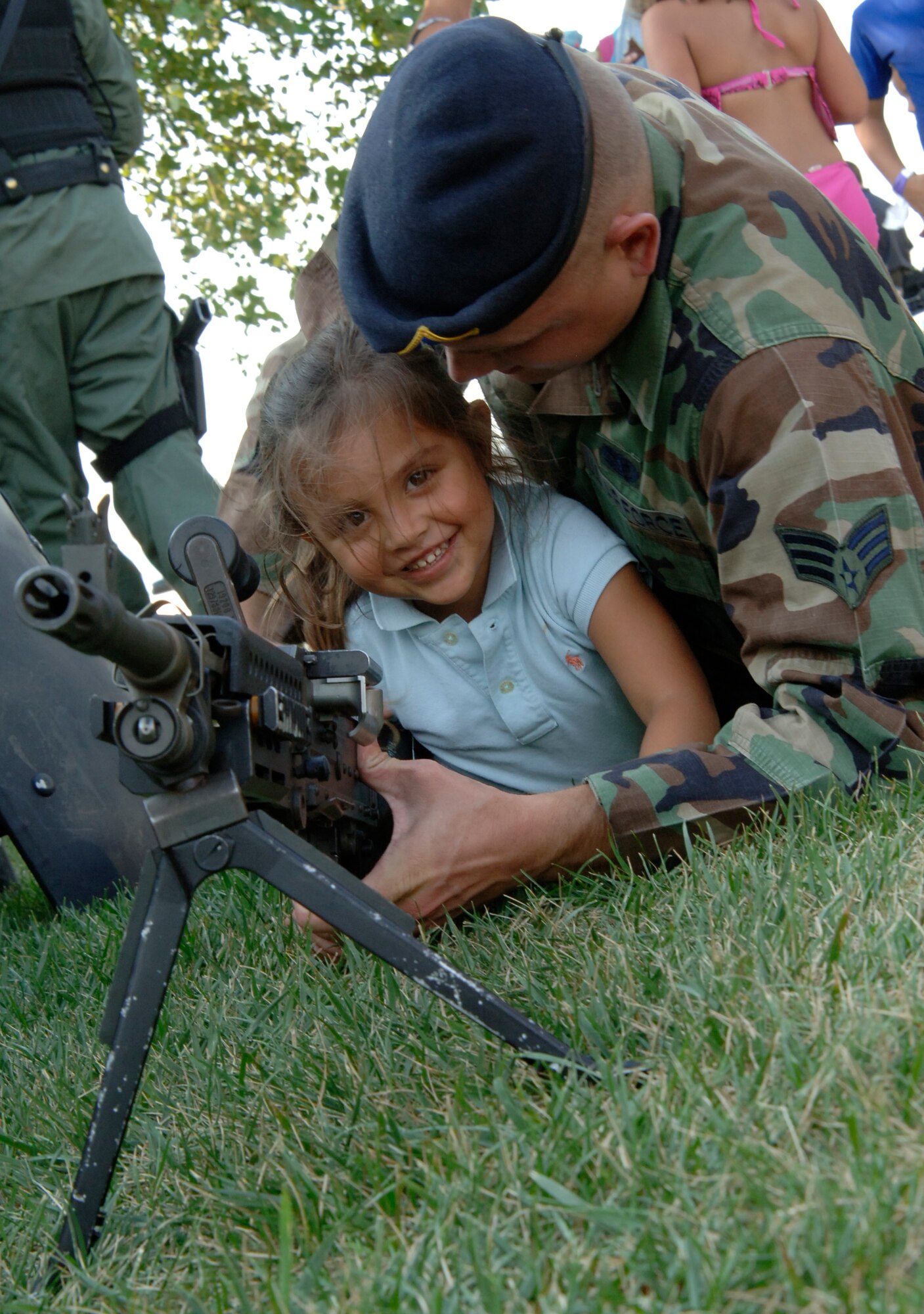MCCONNELL AIR FORCE BASE, Kan. –- Senior Airman Bryan Richter, 22nd Security Forces Squadron, instructs daughter Emily, age four, how to properly hold an M249 machine gun during National Night out at Rock River Rapids in Derby, Aug. 5. The 22nd Security Forces Squadron displayed different types of weapons like the M249 and M240 machine guns during National Night Out. (Photo by Senior Airman Roy Lynch III)