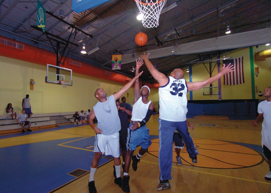 316th Security Forces Squadron members, Staff Sgt. Johnnie Payton, left, and Master Sgt. Charles Mayes, defend against Cana Hypolite, 16, at a scrimmage game held at Youth Center during the 25th Annual National Night Out observance Tuesday.  National Night Out is designed to strengthen neighborhood spirit and police-community partnerships.  (USAF photo by Bobby Jones)