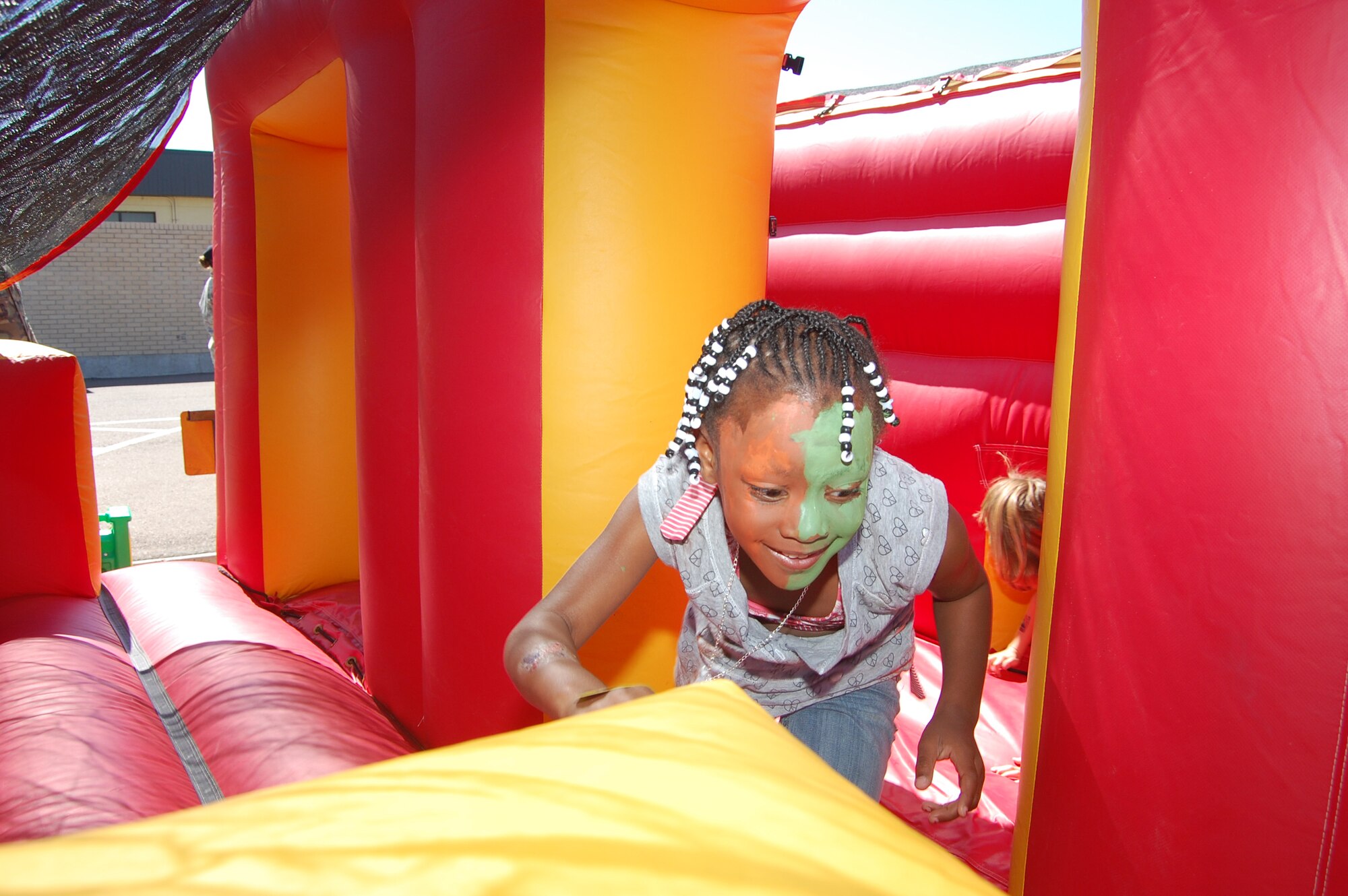 Little Warrior Kennedy, 5, bounces through the end of an obstacle course at the Youth Programs Center's Be Our Guest deployment line Aug. 5. (U.S. Air Force photo/Airman 1st Class Emerald Ralston)