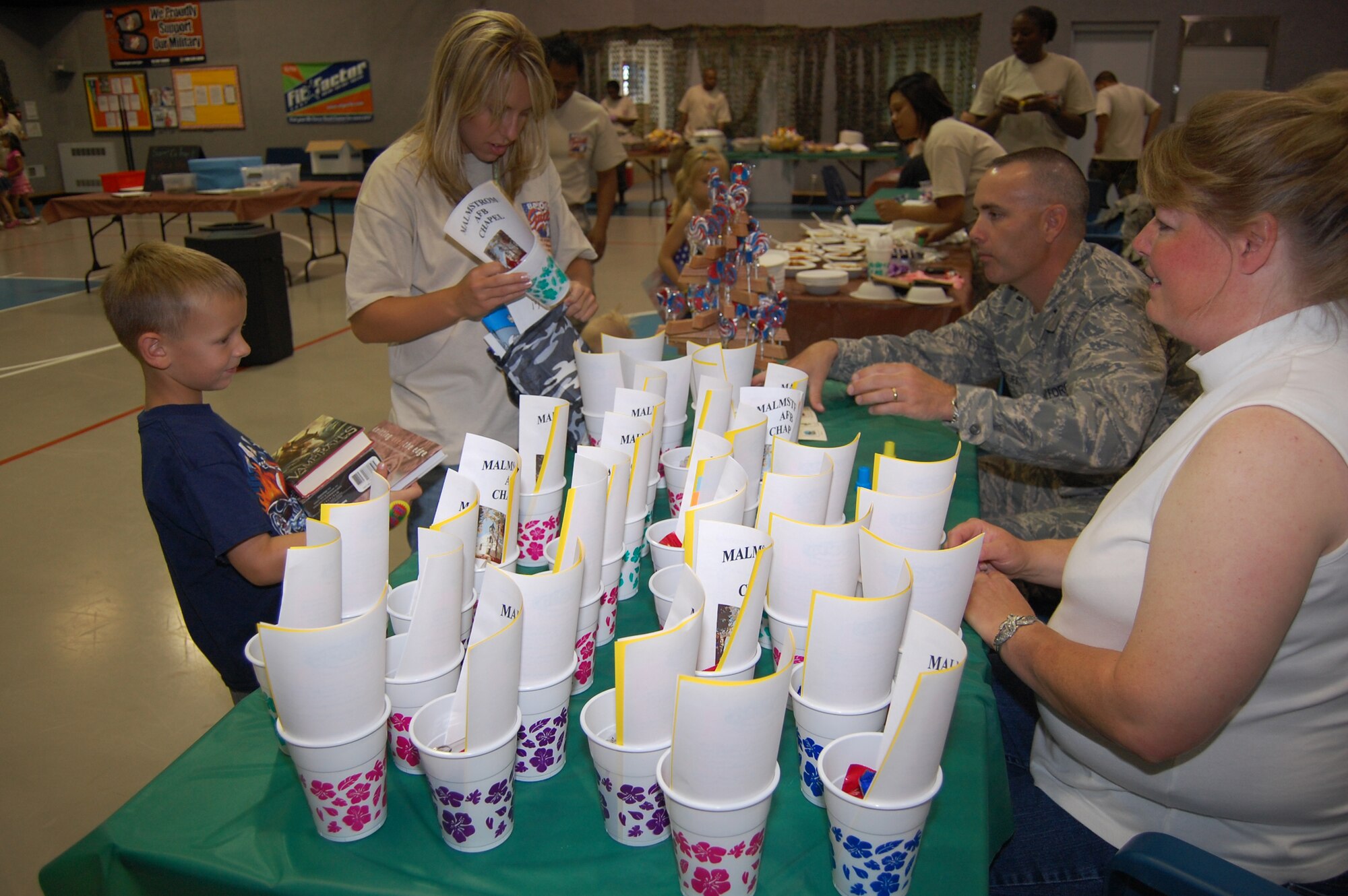 Janet Smith and Chaplain (1st Lt.) Thomas Woodruff, 341st Missile Wing chapel, man the chapel booth during a Be Our Guest mock deployment line held at the Youth Program's Center Aug. 5. The event was held to give the children an idea of what their parents go through when they deploy. (U.S. Air Force photo/Airman 1st Class Emerald Ralston)