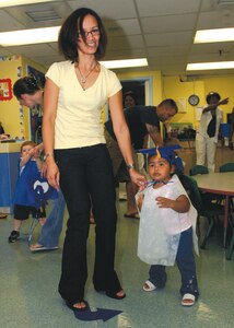 Rami Rice and daughter Jaiyana West, graduate of Infant University, parades around the room during the Infant-Toddler graduation on July 29 in Child Development Center 1. (U.S. Air Force photo by Senior Airman Melissa Stonecipher)