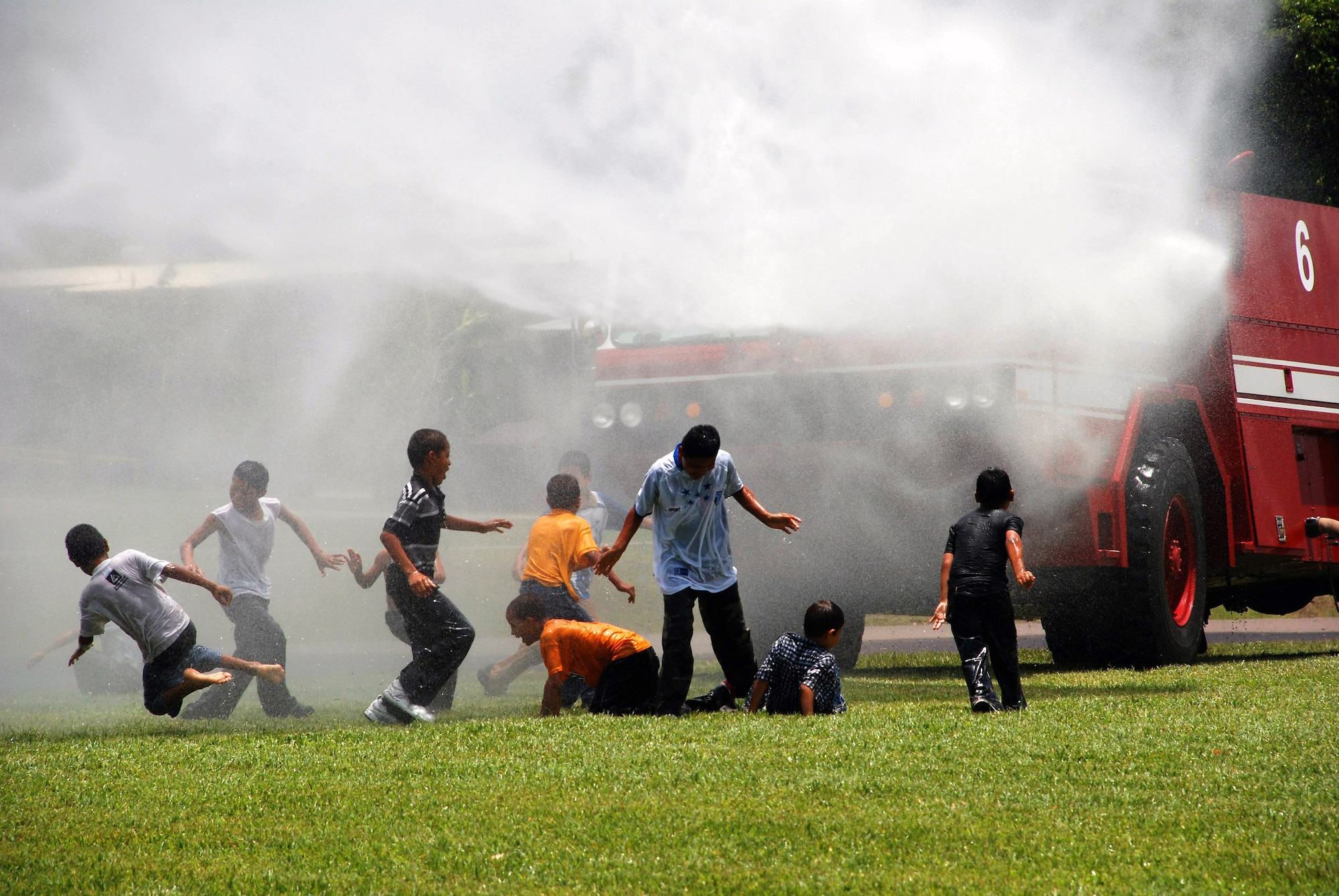 Boys from the Hogar de Ninos Nazareth Orphanage in Comayagua, Honduras, play in the water spray from a Joint Task Force-Bravo fire truck. More than 50 boys from the orphanage came to Soto Cano Air Base, Honduras, Aug. 2 for a day of fun and activities.   (U.S. Air Force photo)