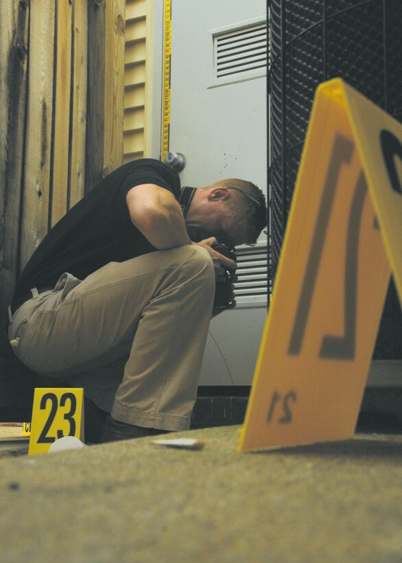 Special Agent Bryan Schmelzer, Forensic Science Consultant, 2nd Field Investigations Squadron, Air Force Office of Special Investigations Region 7, photographs evidence during a training scenario.  The training scenarios help prepare agents to collect evidence during investigations. (U.S. Air Force photo by Airman 1st Class Melissa Rodrigues)