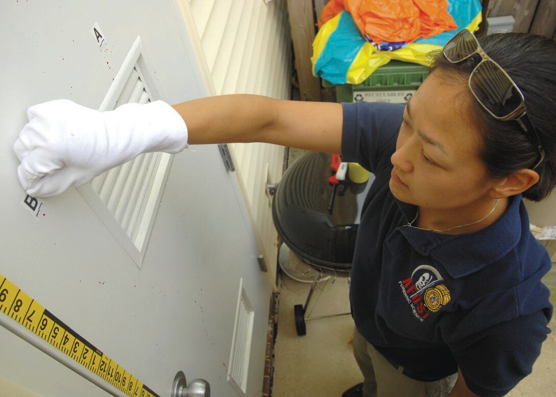 Special Agent Martha Ward, Forensic Science Consultant, 2nd Field Investigations Squadron, AFOSI Region 7, places lettered stickers on evidence during a training scenario. (U.S. Air Force photo by Senior Airman Steven Doty)