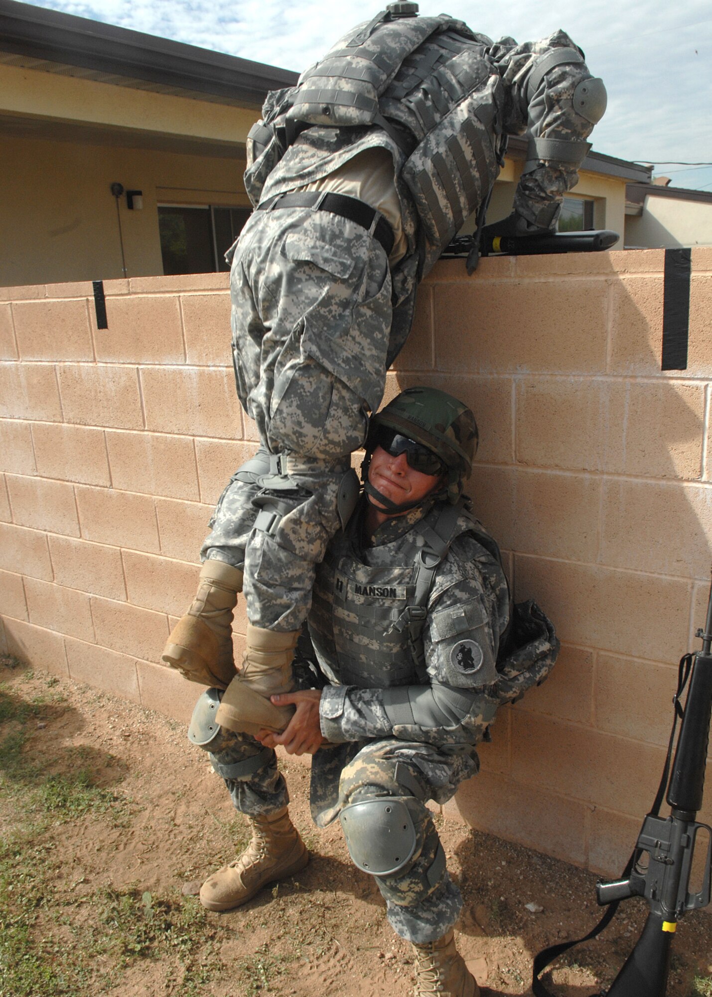 Army Capt. Scott Manson helps Army Lt. Col. Anthony LaPoint, 1st Battlefield Coordination Detachment, over the wall during a training exercise here Aug. 5. Both soldiers are fulfilling their annual Army training readiness requirement during Warrior Tasks and Battle Drills.   Some of the requirements are low crawl, high crawl, movement techniques and a hostage situation. The Army soldiers are a part of the 612th Combined Air Operation Center.  (U.S. Air Force Photo by Senior Airman Jacqueline Romero)
