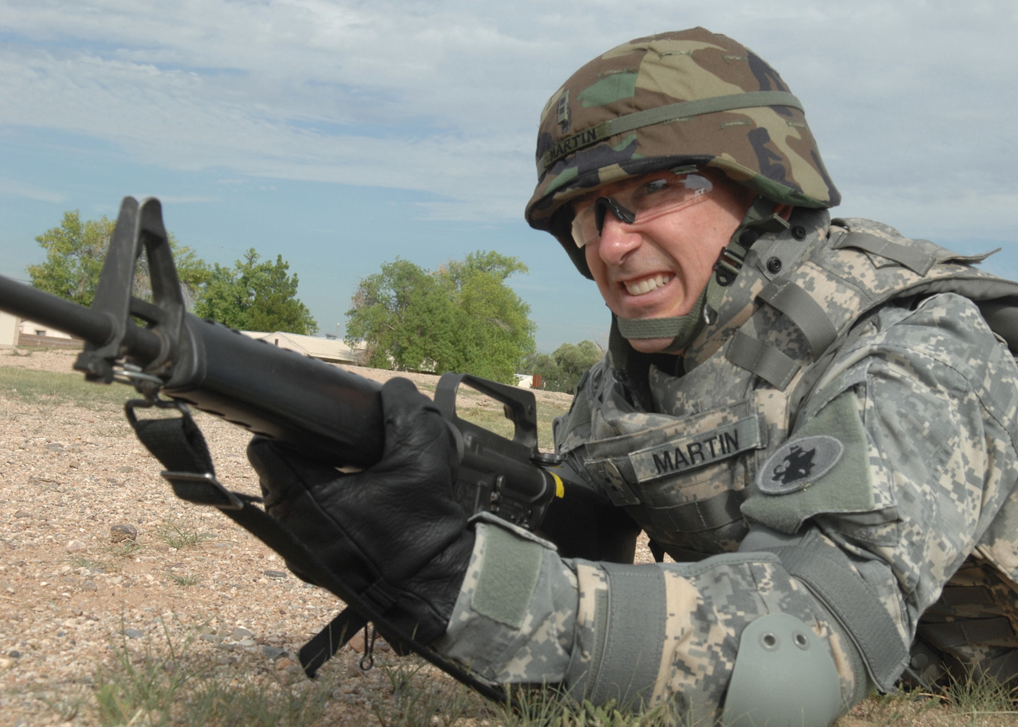 Army Chief Warrant Officer John Martin, 1st Battlefield Coordination Detachment, provides cover during a training exercise here Aug. 5. Chief Warrant Officer Martin looks down range after being fired upon by the enemy during Warrior Tasks and Battle Drills, which is an annual Army training readiness requirement. Some of the requirements that are needed are high crawl, low crawl, movement techniques, entering a building and a hostage situation.  Warrant Officer Martin is a part of the 612th Combined Air Operation Center.  (U.S. Air Force Photo by Senior Airman Jacqueline Romero)