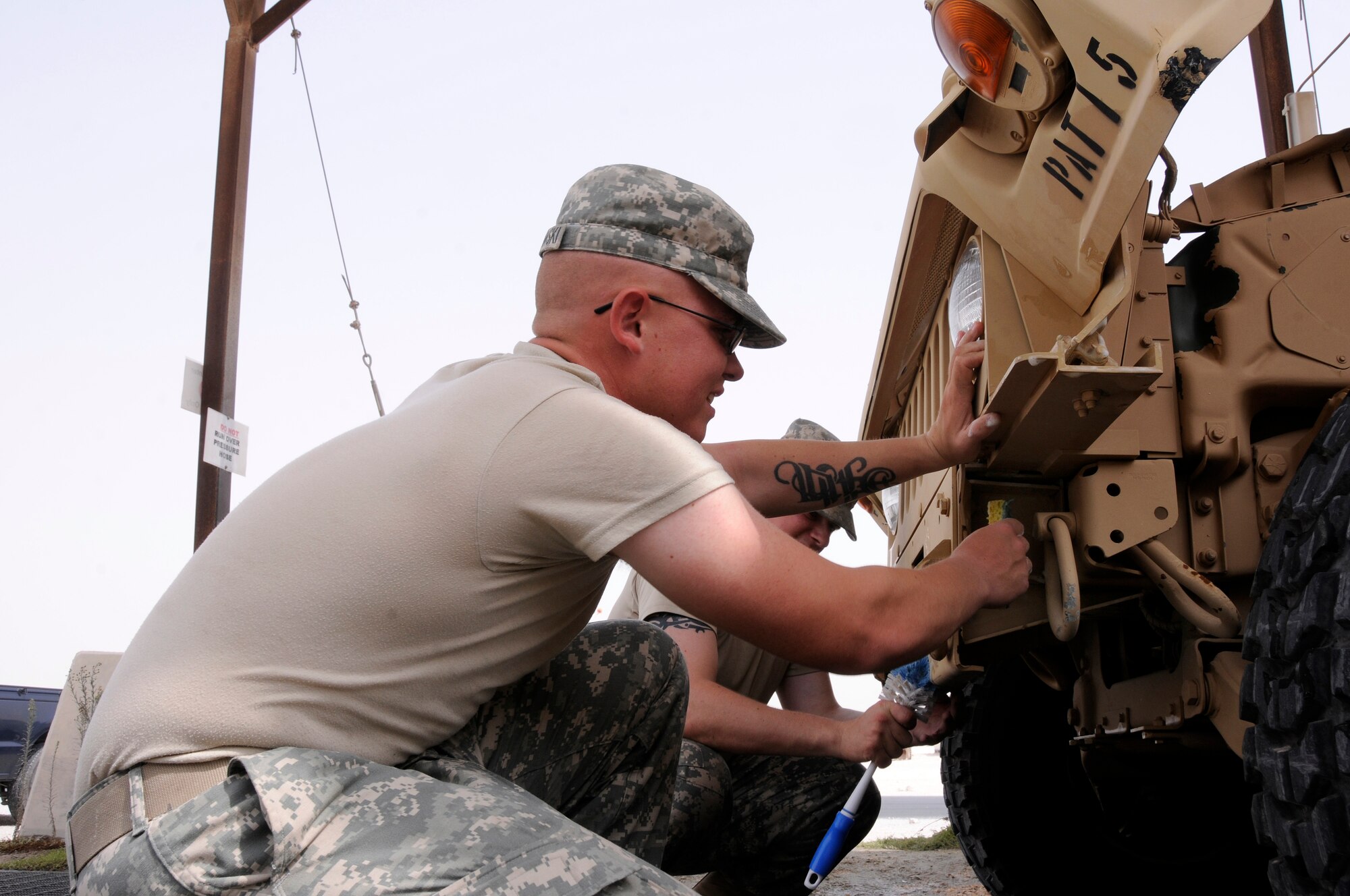 Spc. Josh Polonowski, A 2-43, Air Defense Artillery from Fort Bliss, Texas, uses a scrubbing pad and Private 1st Class Kyle Page, A 2-43, ADA, uses a toilet brush on the front of a Battery Command Post (BCP) vehicle Aug. 7, 2008.  The soldiers are cleaning all dirt, mud, grease and oils from the BCP in preparation for shipping it back to Texas from an undisclosed airbase in Southwest Asia.  (U.S. Air Force photo by Tech. Sgt. Michael Boquette/RELEASED)