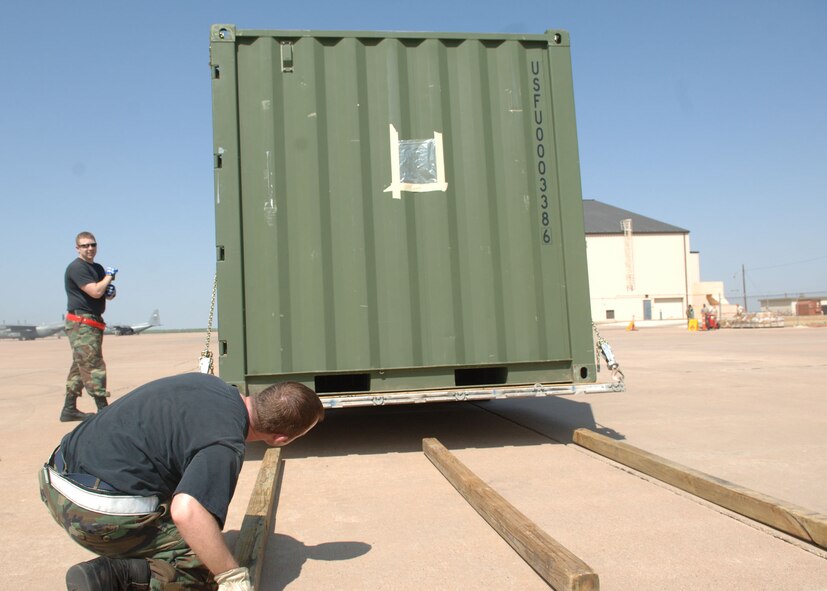 DYESS AIR FORCE BASE, TEXAS -- Staff Sergeant Mayan Jarnagin places cedar poles underneath a loaded cargo palette during the Cargo Rodeo, July 30. Due to the use of forklifts, all cargo in a rodeo must be strapped down to a cargo palette to ease the loading and transportation procedures of the cargo. (U.S. Air Force Photo by Airman 1st Class Micheal Breaux).