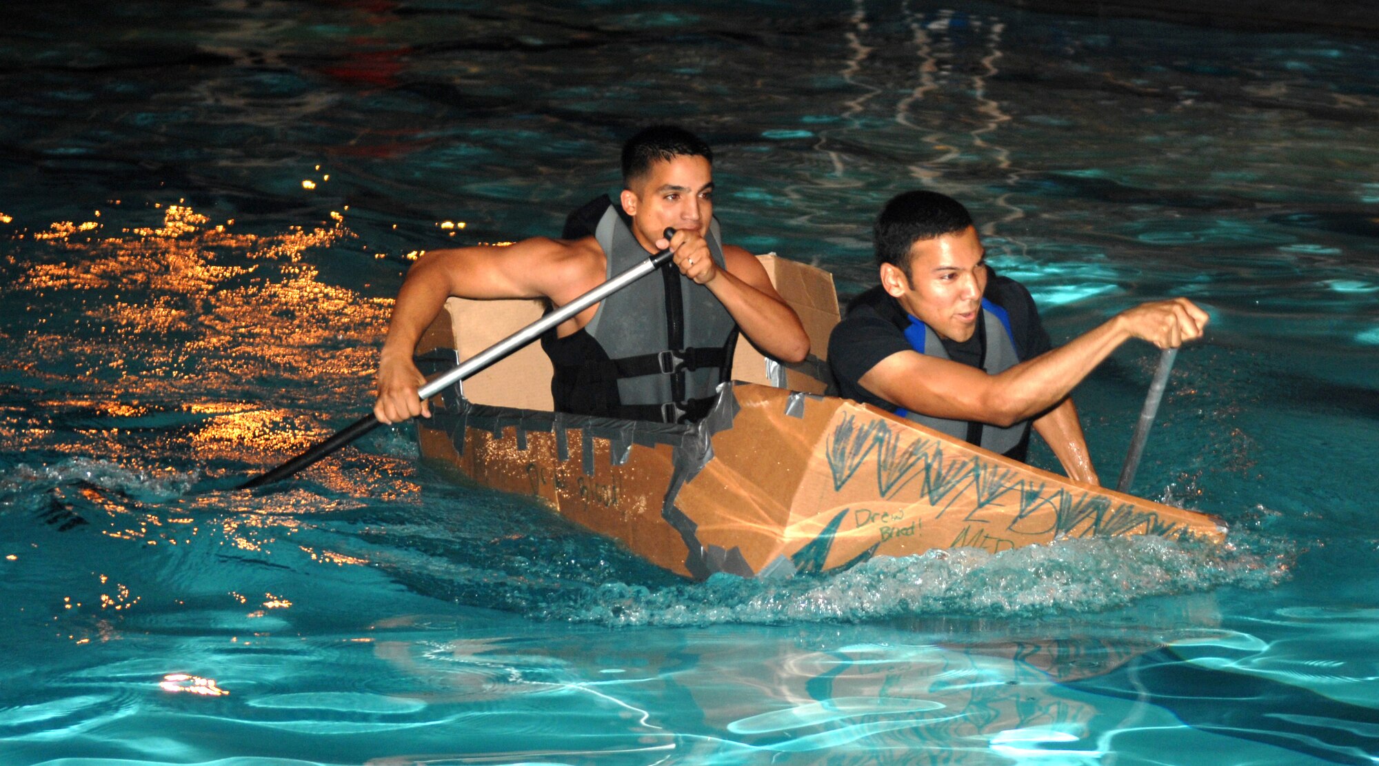 Airman 1st Class Carlos Villegas and Airman 1st Class Broland Johnson from the 4th Medical Operations Squadron race their newly-constructed cardboard boat during the Build-a-Boat competition August 1, 2008, Seymour Johnson Air Force Base, North Carolina. The Build-a-Boat competition's purpose was to boost morale and help Airman meet other Airman. (U.S. Air Force photo by Airman 1st Class Gino Reyes) 