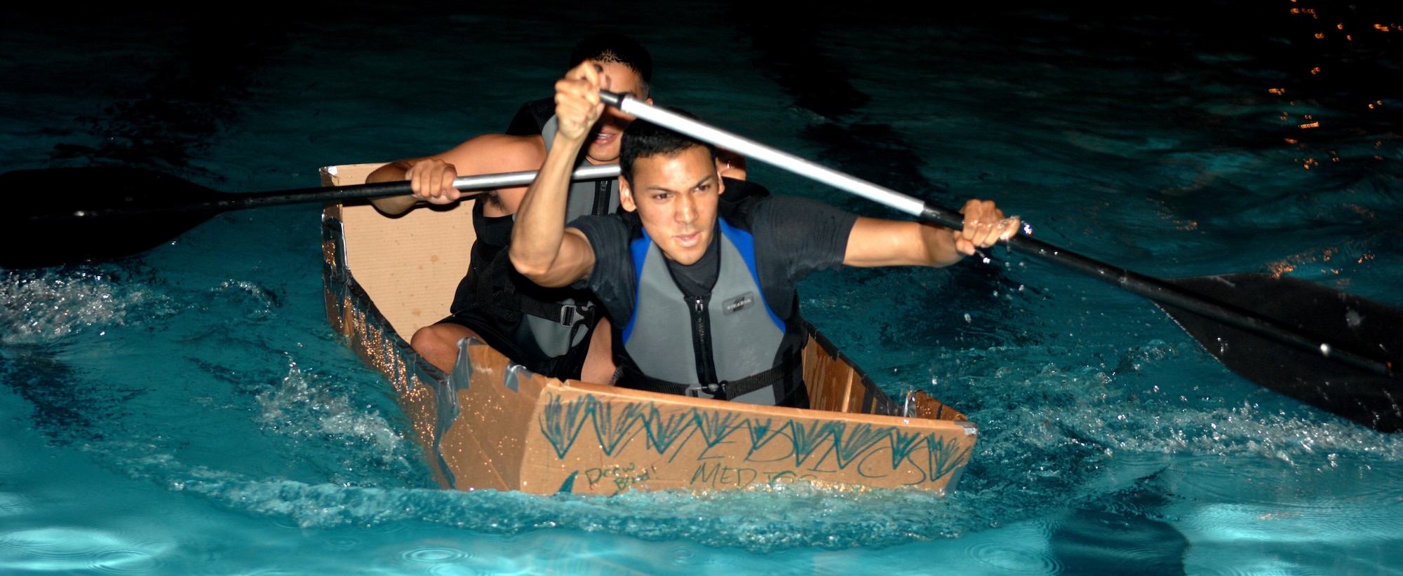 Airman 1st Class Carlos Villegas and Airman 1st Class Broland Johnson from the 4th Medical Operations Squadron paddle vigorously to beat out the other competitors during the Build-a-Boat competition August 1, 2008, Seymour Johnson Air Force Base, North Carolina. The Build-a-Boat competition's purpose is to boost morale and help Airman meet other Airman. (U.S. Air Force photo by Airman 1st Class Gino Reyes)
