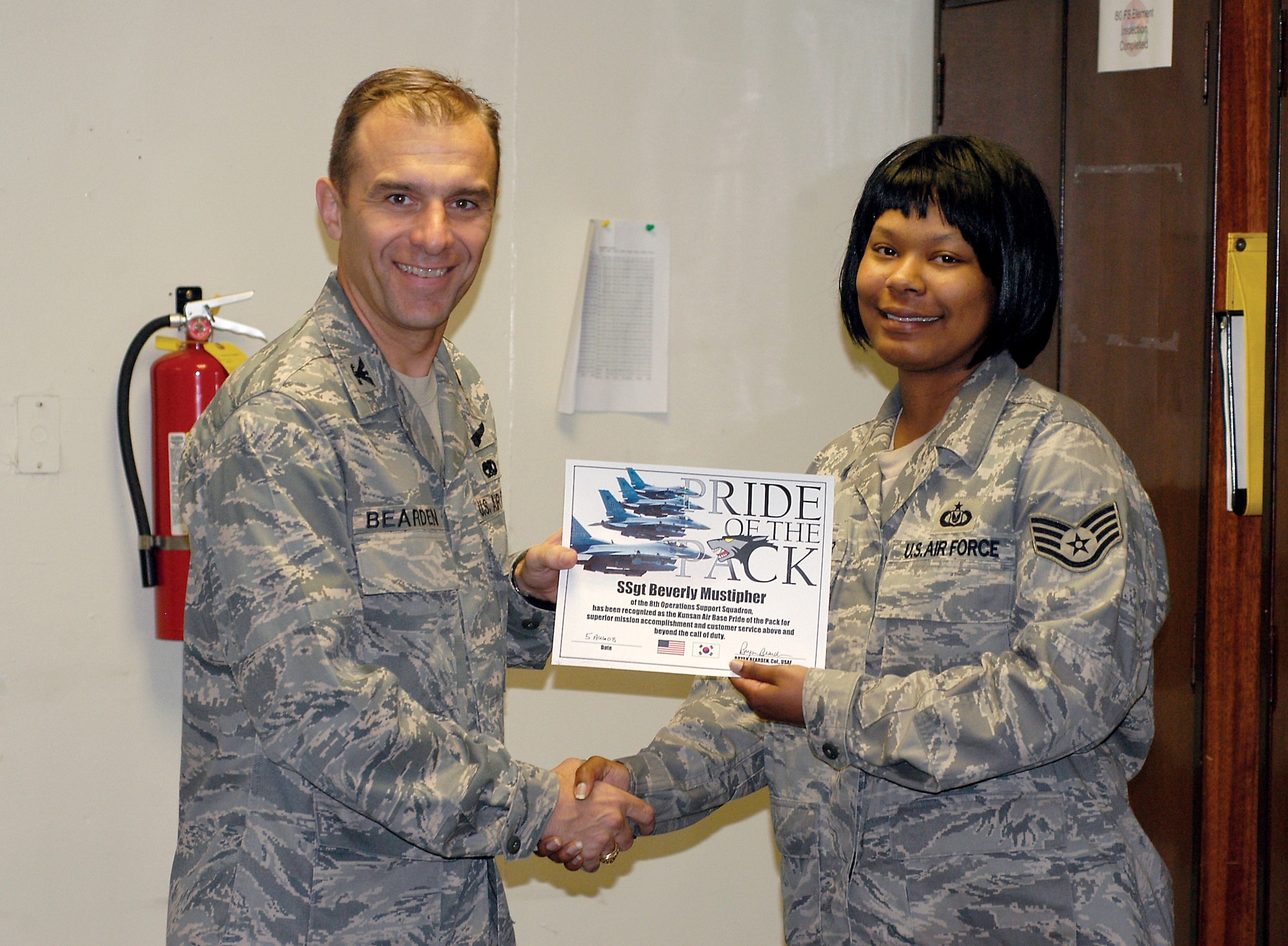 Colonel Bryan Bearden, 8th Fighter Wing commander, presents Staff Sgt. Beverly Mustipher, 8th Operations Support Squadron, with her Pride of the Pack certificate Aug. 6. (U.S. Air Force Photo)