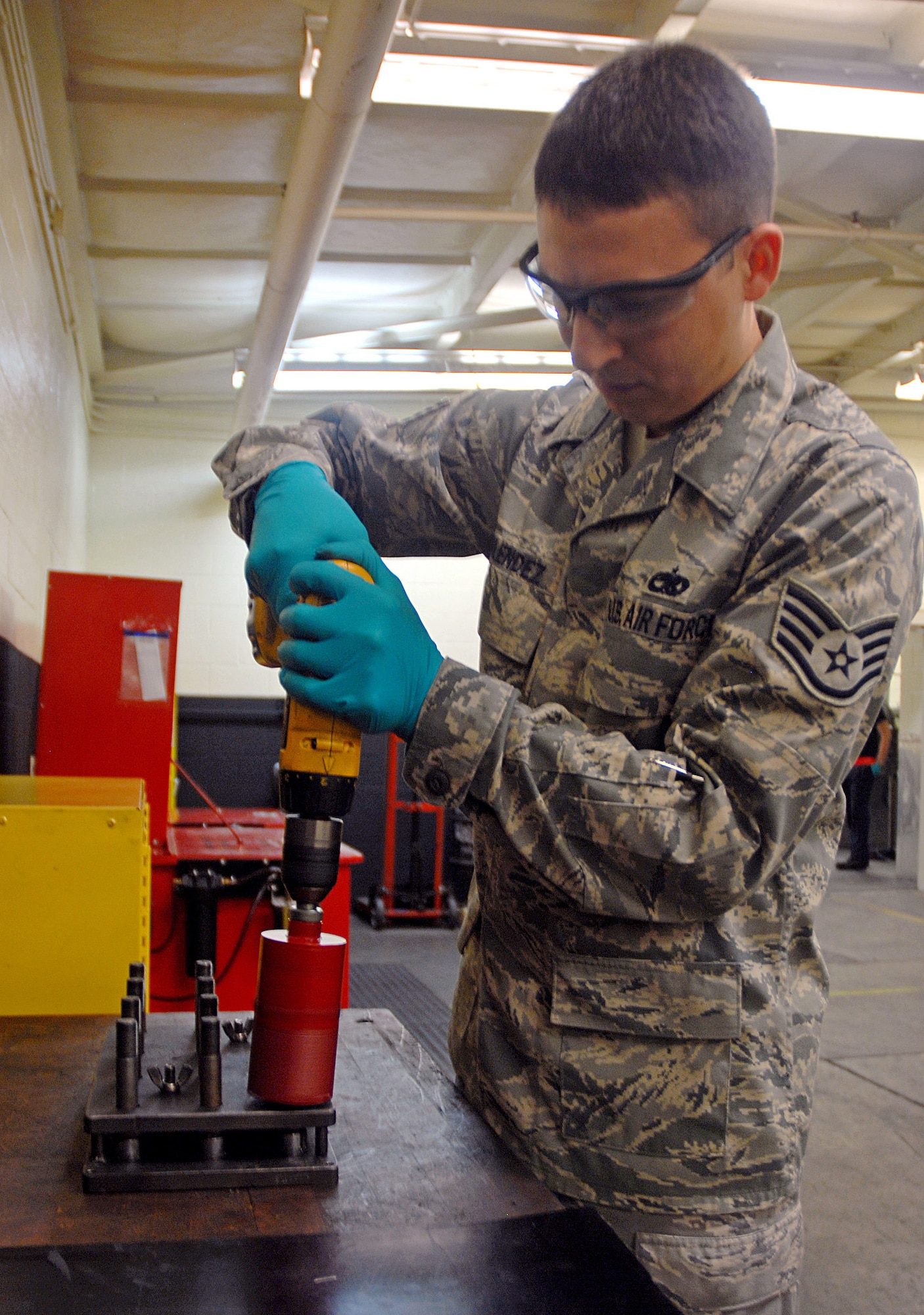 Recently promoted Tech. Sgt. Eddie Melendez cleans C-17 nose-wheel  bolts with a power drill and brush cleaner July 24 at the 437th Maintenance Squadron wheel and tire shop at Charleston Air Force Base, S.C.  Because of a change he developed for cleaning the bolts, it now takes a minute and 15 seconds to clean 12 bolts compared to the more than an hour it took prior to the change. Sergeant Melendez is an aircraft maintenance craftsman with the 437 MXS. (U.S. Air Force photo/Staff Sgt. Jennifer Arredondo)
