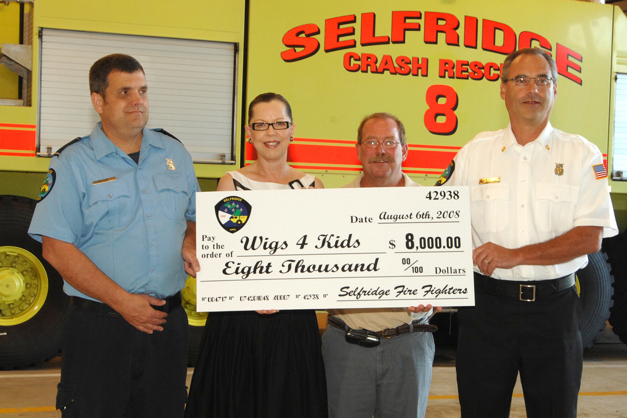 Selfridge Fire Chief Mark Palm (right) presents a check for $8000 to Maggie Varney, founder and CEO of Wigs for Kids, a local Michigan charity that provides wigs for children who have suffered hair loss from the result of illness. Max Corning (left), Selfridge firefighter, and Dan Peterek of the Detroit Chapter Parrot Head Club assisted in the Selfridge Firefighters Annual Golf Outing which rasied the funds in July. 