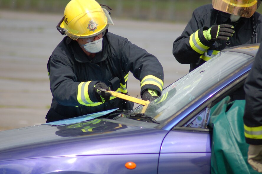 A Fireman from the RAF Molesworth Fire Department uses a special tool to break through a windshield to free a "victim" during a "Jaws of Life" demonstration at RAF Molesworth on August 7th.  (Photo by Mr. Steven Turner)
