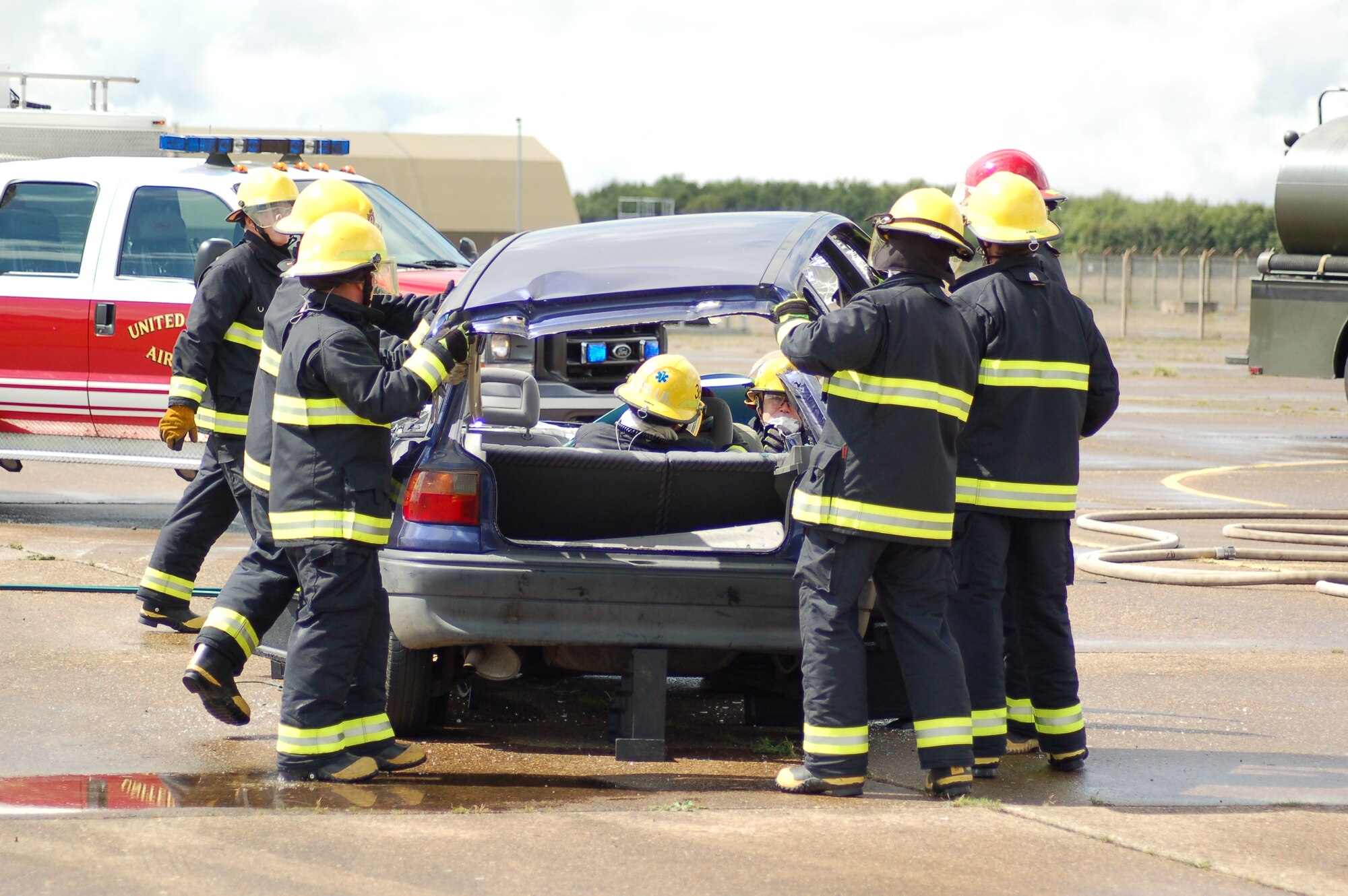 Firemen from the Royal Air Force Molesworth Fire Department remove the roof of a vehicle involved in a simulated accident after the roof was cut off by the "Jaws of Life" in a demonstration on August 7.  The demonstration on RAF Molesworth was sponsored by the JAC Safety Officer, Staff Sgt. Trisha S. Edgar.  (Photo by Mr. Steven Turner)