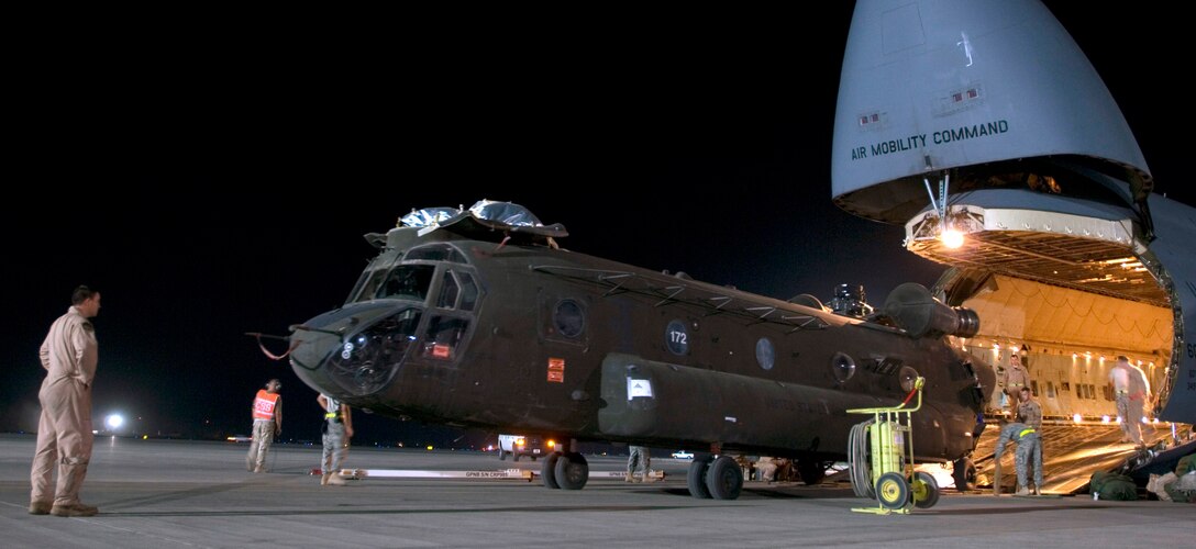 A C-5 Galaxy crew loads a CH-47D Chinook helicopter into its cargo bay at Joint Base Balad, Iraq. The base processes more than 950 cargo aircraft, 12,000 tons of cargo and 19,000 passengers per month, making it one of the busiest aerial port operations in the Department of Defense. (U.S. Air Force photo/Airman 1st Class Jason Epley)