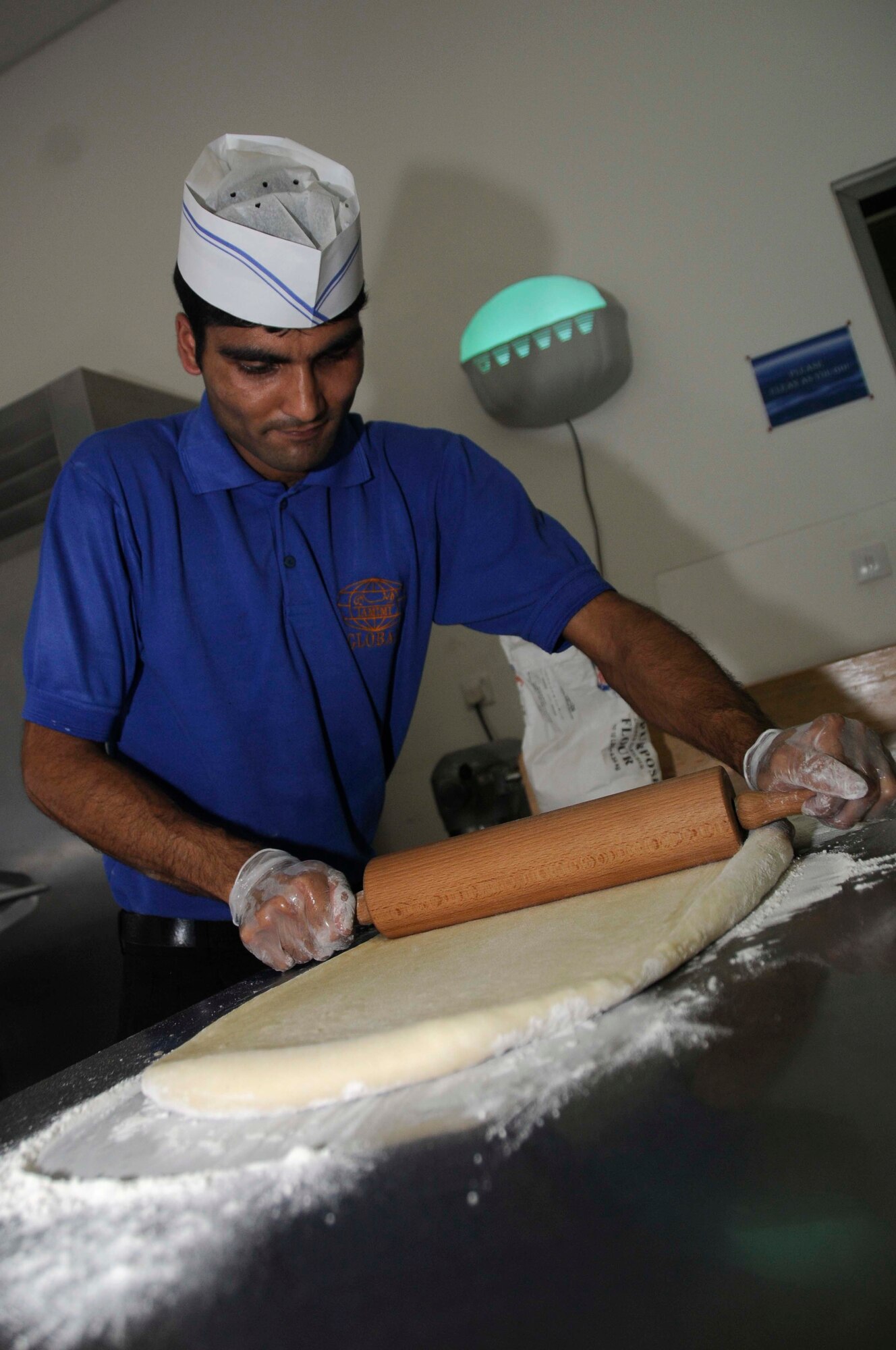 Chandra Acharya uses a rolling pin to roll flour into dough to make pecan rolls at a dining facility Aug. 5, at an undisclosed location in Southwest Asia. (U.S. Air Force photo by Staff Sgt. Darnell T. Cannady)