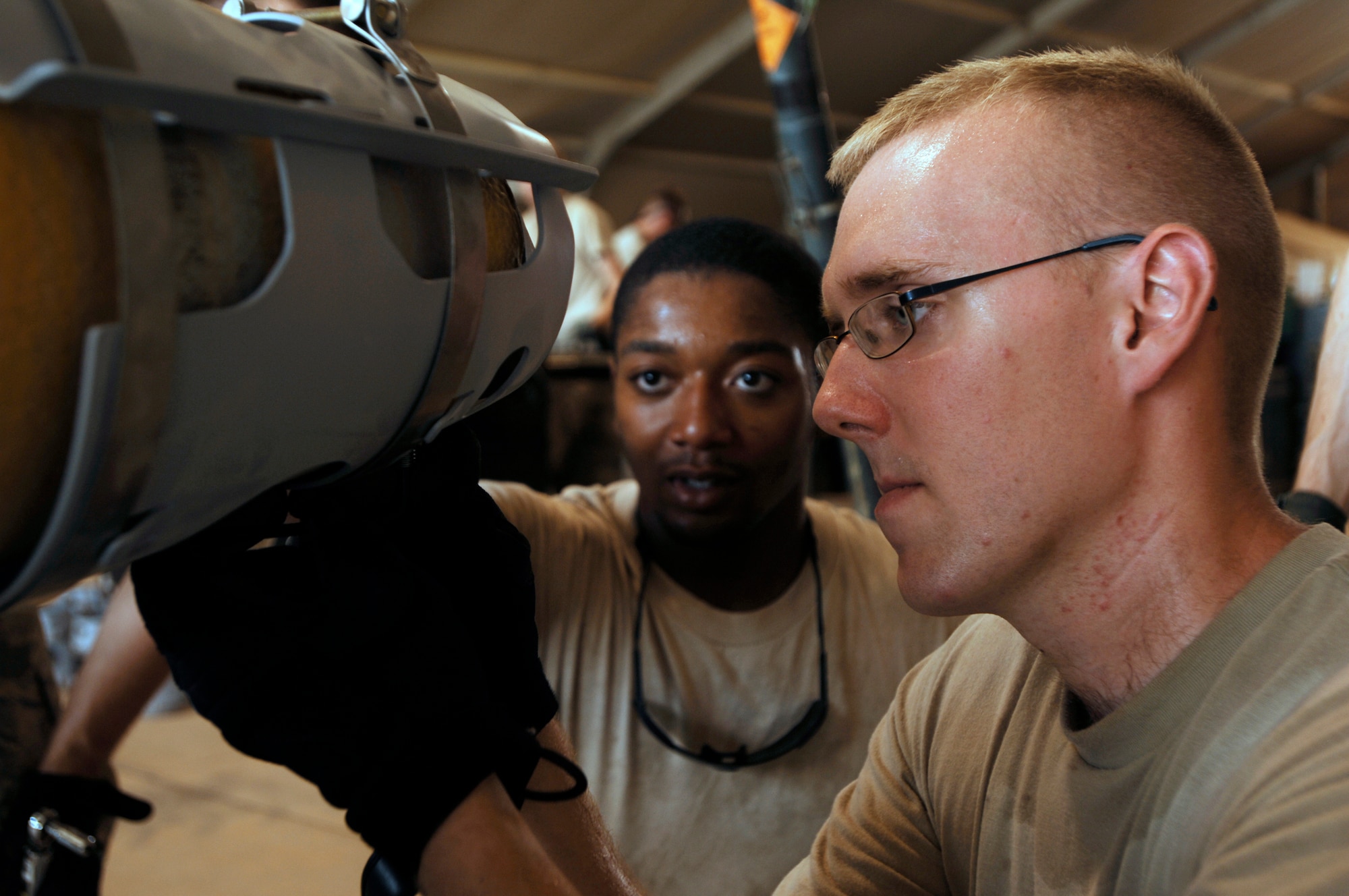 JOINT BASE BALAD, Iraq -- Airman 1st Class Jon Elkins (right) installs a strake assembly onto a GBU-38 Joint Direct Attack Munition here Aug. 7 with the help of Airman 1st Class Antione Eaddy. The JDAM contains an inertial navigational system and a GPS guidance control unit that improves the accuracy of general purpose bombs in any weather condition. Airmen Elkins and Eaddy are munitions handlers with the 332nd Expeditionary Maintenance Squadron. Airman Elkins is deployed from Fairchild Air Force Base, Wash., and is originally from Tucson, Ariz. Airman Eaddy is deployed from Shaw Air Force Base, S.C. His hometown is Detroit. (U.S. Air Force photo/Airman 1st Class Jason Epley)