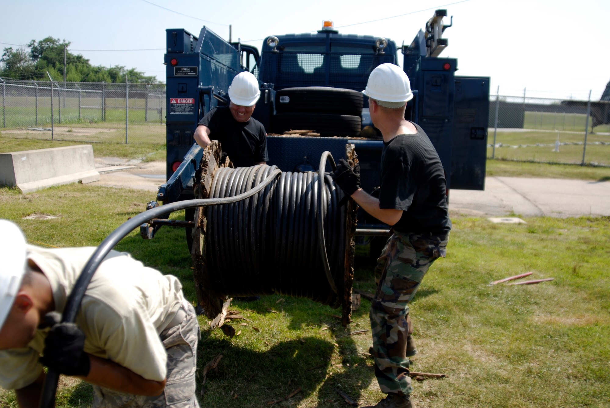 U.S. Air Force Senior Airman George Perez Jr., Staff Sgt. Dale Winn and Staff Sgt. Alberto Martinez, 8th Communications Squadron cable technicians,  struggle to pull communications wire off of a broken spool on Kunsan AB, South Korea, 08 Aug 2008.  (U.S. Air Force photo/Staff Sgt. Jason Colbert)