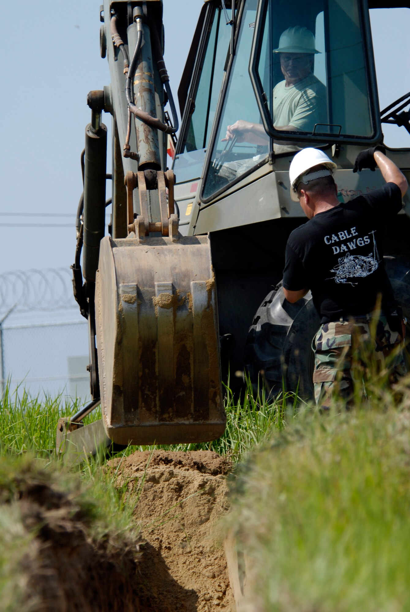 U.S. Air Force Tech Sgt. Richard Thompson, 8th Communications Squadron Cable Technician, pilots a back hoes while Staff Sgt. Alberto Martinez directs where to dig his trench for communication wires on Kunsan AB, South Korea, 08 Aug 2008.  (U.S. Air Force photo/Staff Sgt. Jason Colbert)