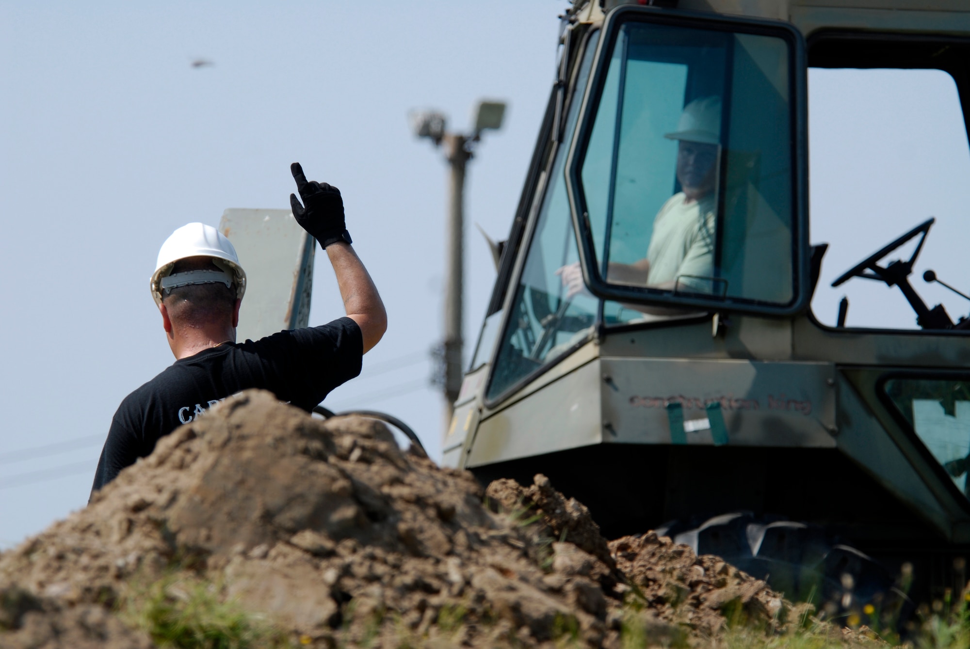 U.S. Air Force Tech Sgt. Richard Thompson, 8th Communications Squadron Cable Technician, pilots a back hoes while Staff Sgt. Alberto Martinez directs where to dig his trench for communication wires on Kunsan AB, South Korea, 08 Aug 2008.  (U.S. Air Force photo/Staff Sgt. Jason Colbert)
