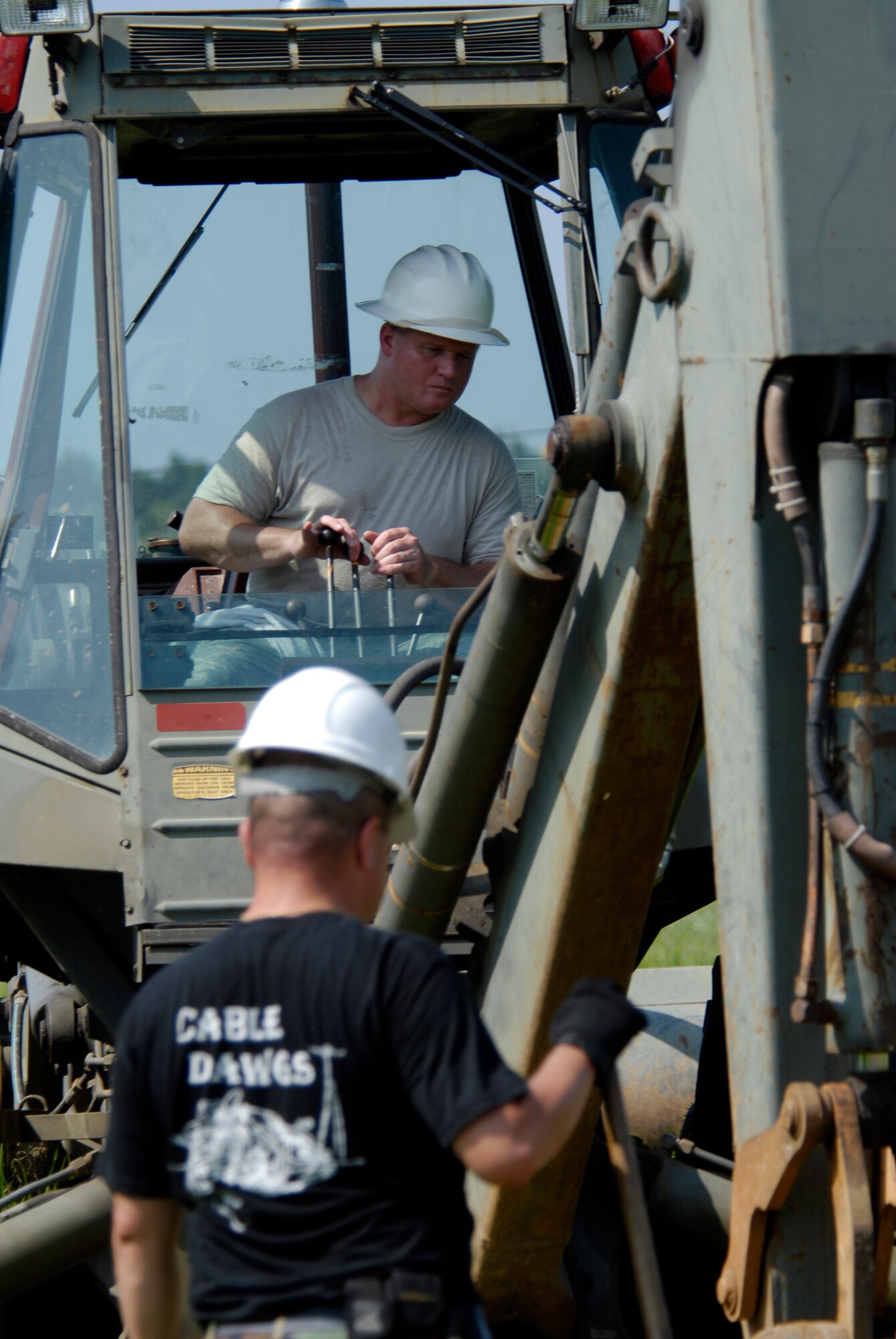 U.S. Air Force Tech. Sgt. Richard Thompson, 8th Communications Squadron Cable Technician, pilots a back hoes while Staff Sgt. Alberto Martinez directs where to dig his trench for communication wires on Kunsan AB, South Korea, 08 Aug 2008.  (U.S. Air Force photo/Staff Sgt. Jason Colbert)