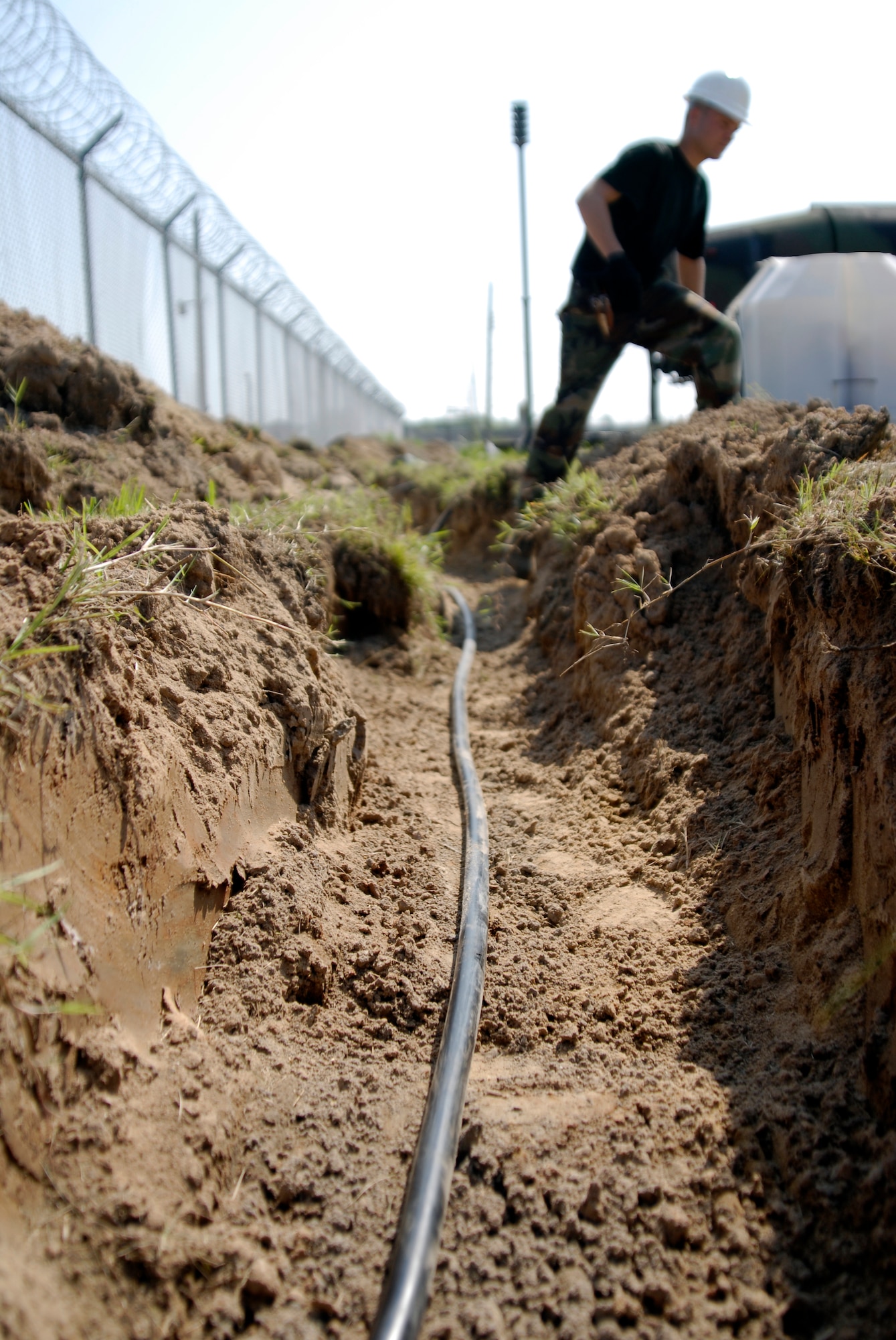 U.S. Air Force Staff Sgt. Dale Winn, 8th Communications Squadron Cable Technician, jumps out of a trench where he just laid communication cable to enable faster communication with the F-16 pilots assigned to Kunsan AB, South Korea, 08 Aug 2008.  Faster communication allows leaders to be relayed up to the moment battle statistics, helping them make better decisions. (U.S. Air Force photo/Staff Sgt. Jason Colbert)