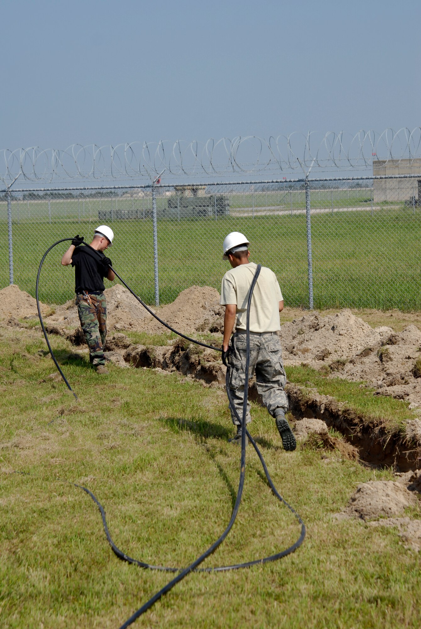 U.S. Air Force Staff Sgt. Dale Winn and Senior Airman George Perez Jr., 8th Communications Squadron Cable Technicians, pull communication cable that will be laid to enable faster communication with the F-16 pilots assigned to Kunsan AB, South Korea, 08 Aug 2008.  Faster communication allows leaders to be relayed up to the moment battle statistics, helping them make better decisions. (U.S. Air Force photo/Staff Sgt. Jason Colbert)