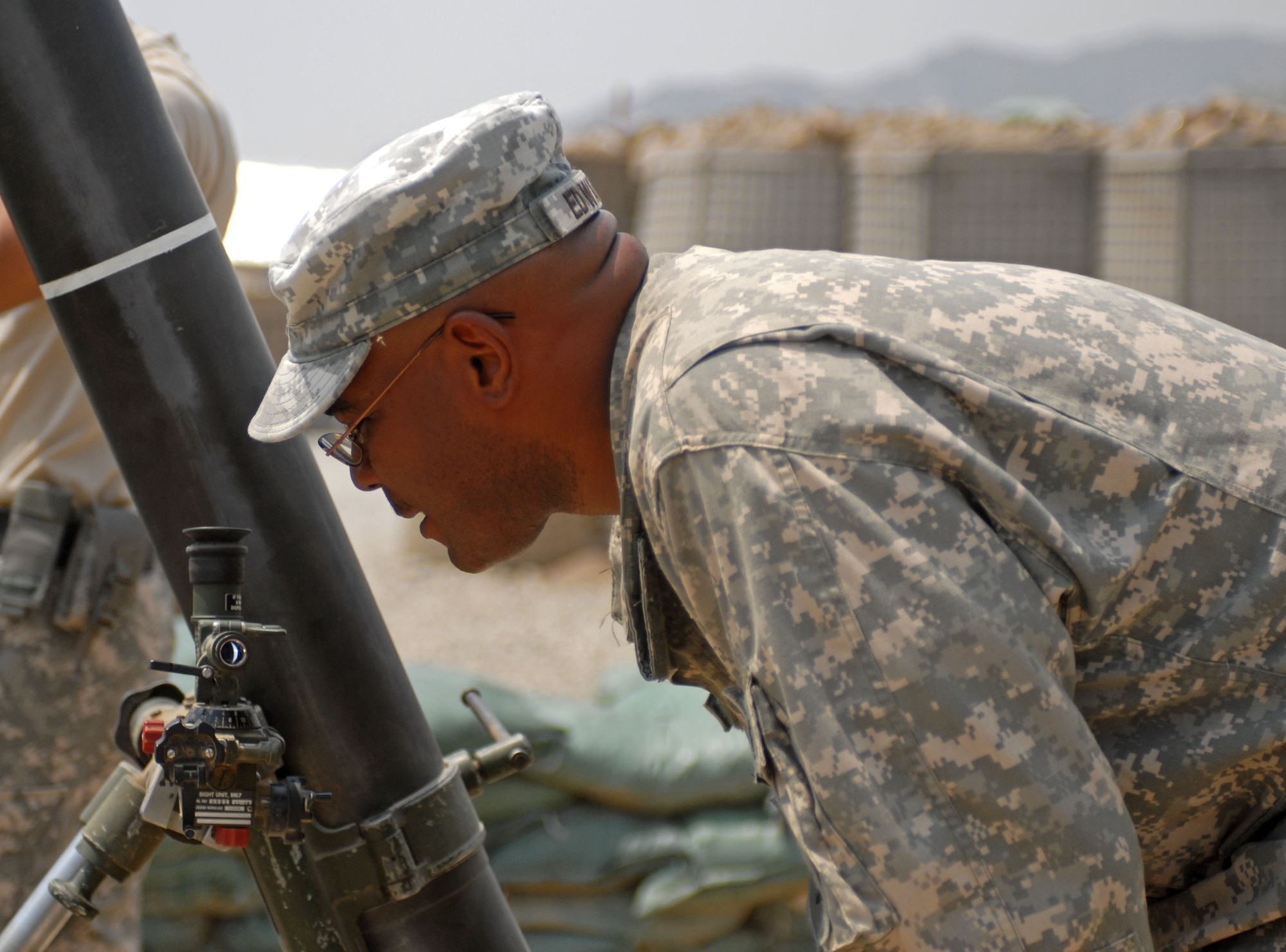 Army Staff Sgt. Jerome Edwards, 1st Battalion, 6th Field Artillery, 3rd Brigade Combat Team, 1st Infantry Division, looks through the scope of a mortar tube to ensure accuracy, at Forward Operating Base Kala Gush, Afghanistan, July 30. (U.S. Army photo/ Staff Sgt. Adora Medina)