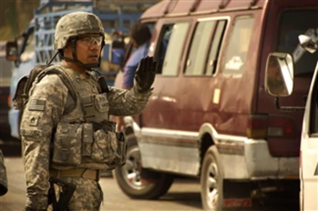 U.S. Army Staff Sgt. Conrad Vasquez directs traffic on a road leading into Baghdad, Iraq, on July 31, 2008.  Vasquez is assigned to the 2nd Squadron, 14th Cavalry Regiment, 25th Infantry Division.  
