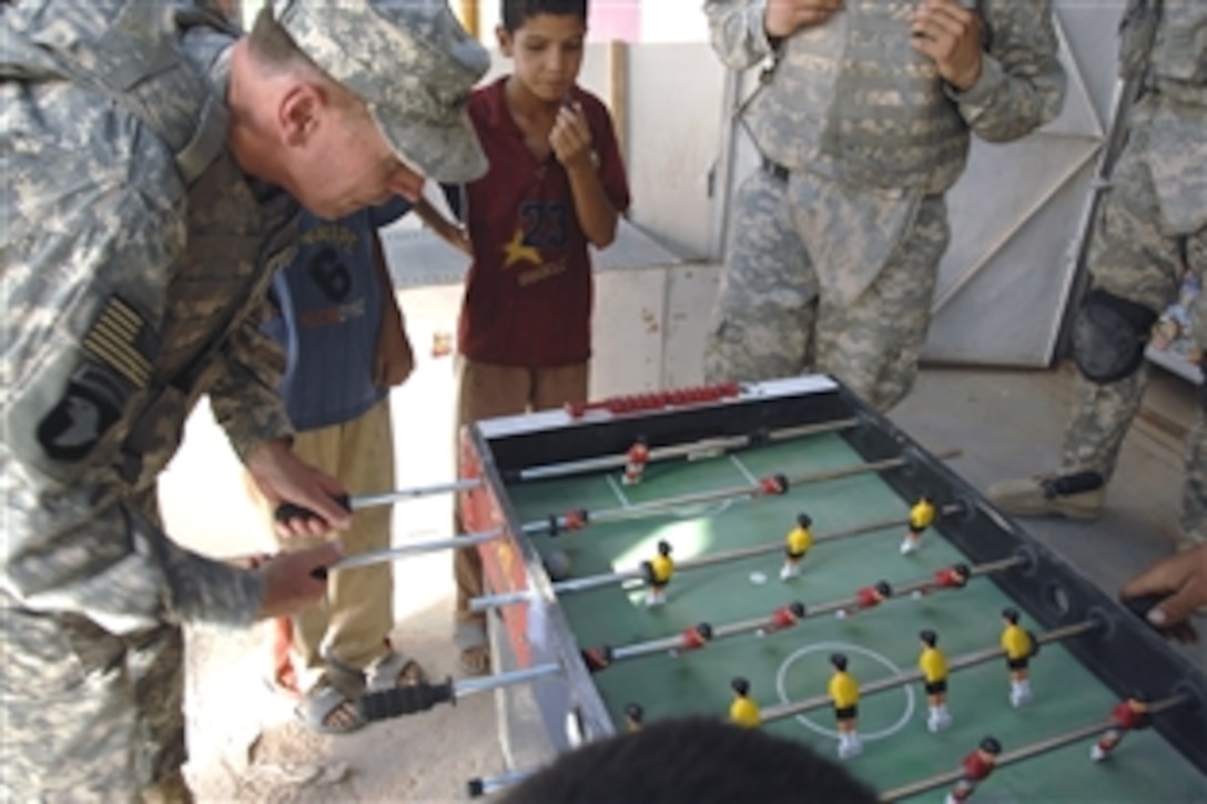 U.S. Army Gen. David Petraeus, commanding general of Multinational Force Iraq, plays foosball with Iraqi children while touring a market in Abu Ghraib, Iraq, Aug. 2, 2008.  