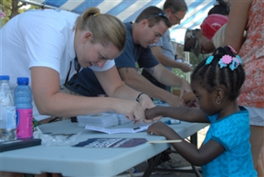 U.S. Navy Petty Officer 1st Class Karyn Sigurdsson finger prints a child at the Ident-A-Kid booth during National Night Out at Naval Station Rota, Spain, on Aug. 5, 2008.  The community event was coordinated by the station after a four-year absence with support from station security and local Spanish police departments.  National Night Out is a program designed to heighten crime and drug prevention awareness, generate support for and participation in local anti-crime programs and to strengthen neighborhood spirit and police community partnerships. 