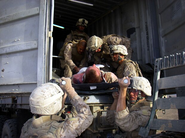Navy Lieutenant Tony A. Wade (left), an STP trauma nurse and Jacksonville, N.C., native, bandages a wounded Marine as fellow Marines of Company F, TF 2/7, remove him from the Mobile Trauma Bay after being wounded in a firefight with members of the Taliban. (Photo by Navy Hospitalman Dan K. Marker)